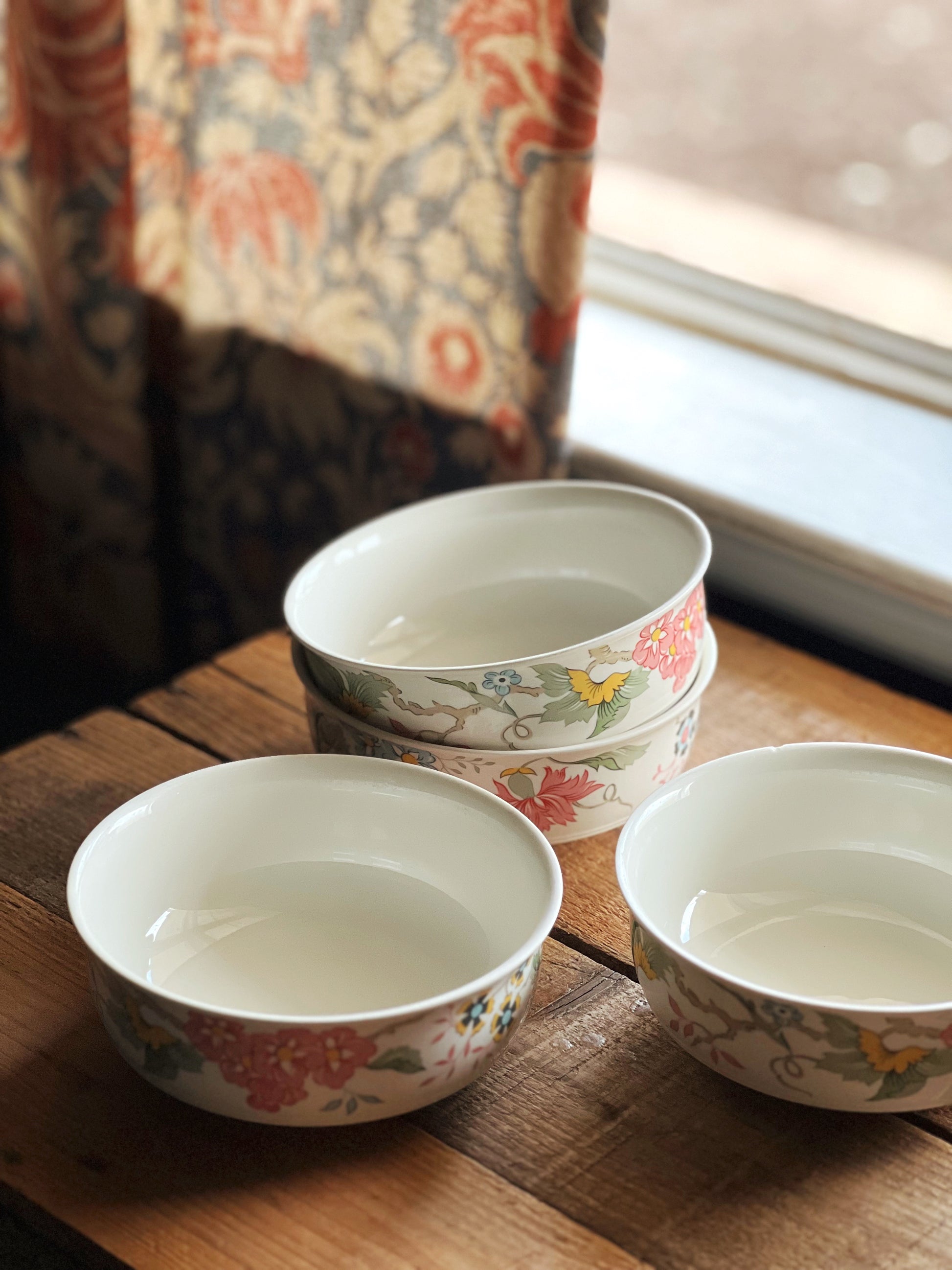 four multi color floral cereal bowls on a tabletop