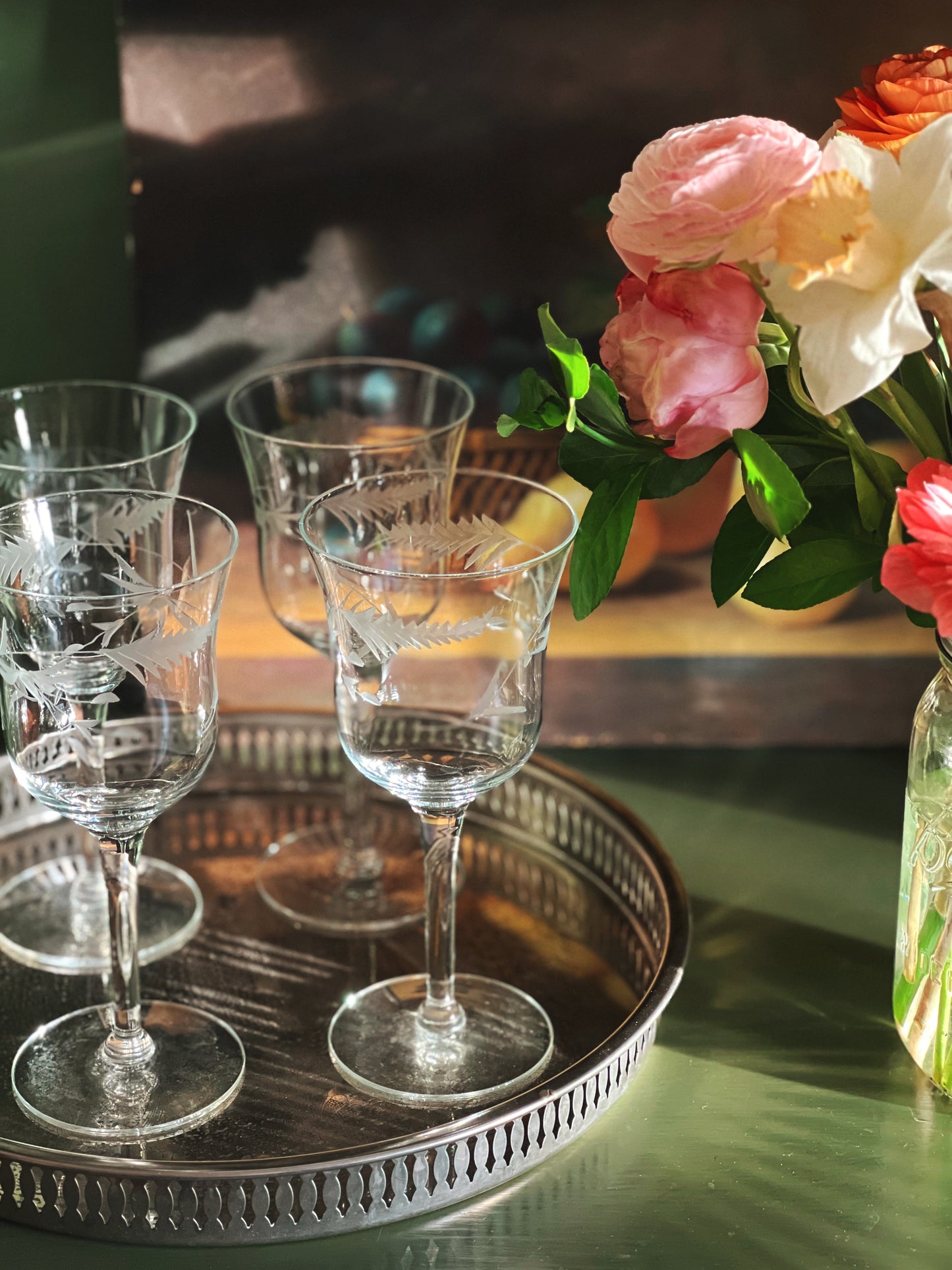 four etched wine glasses on a silver tray