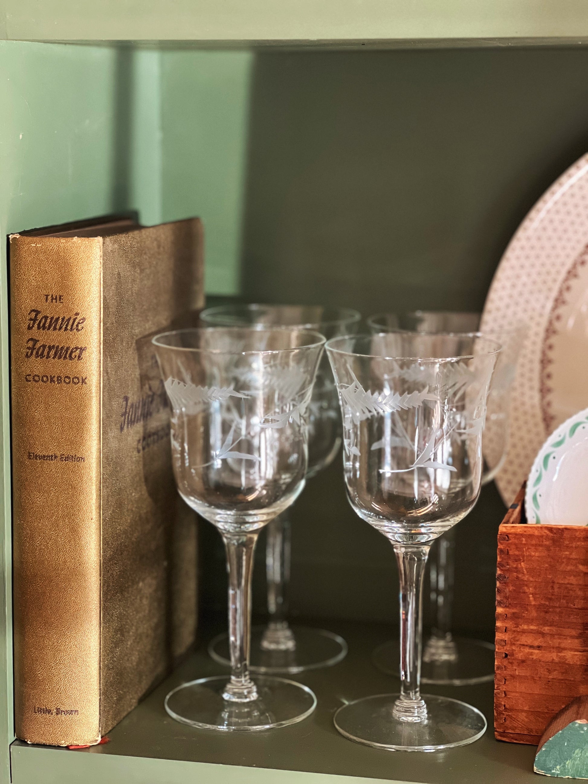 vintage cookbook on a shelf with wine glasses
