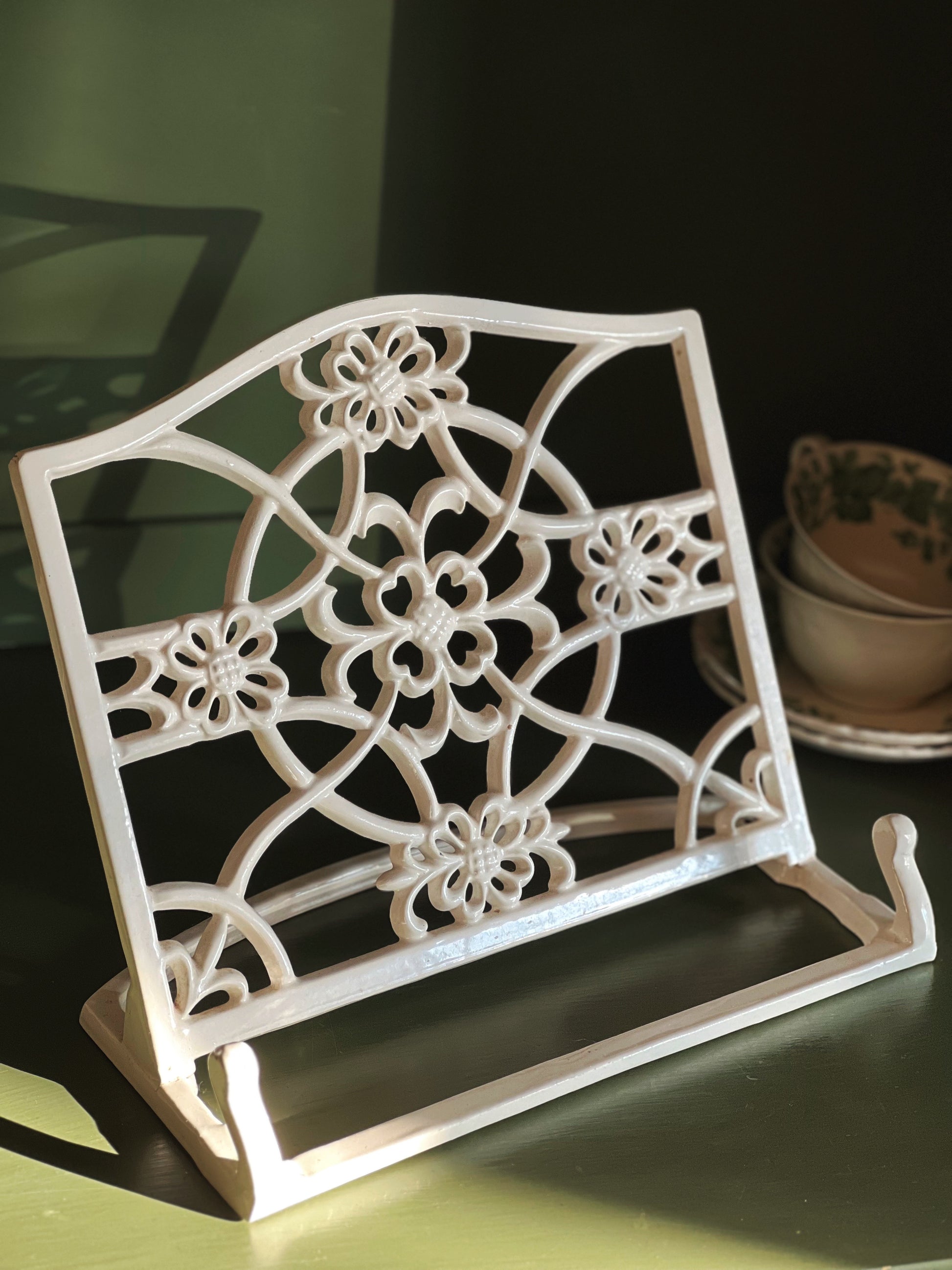 Decorative white metal rack with floral patterns on a dark surface