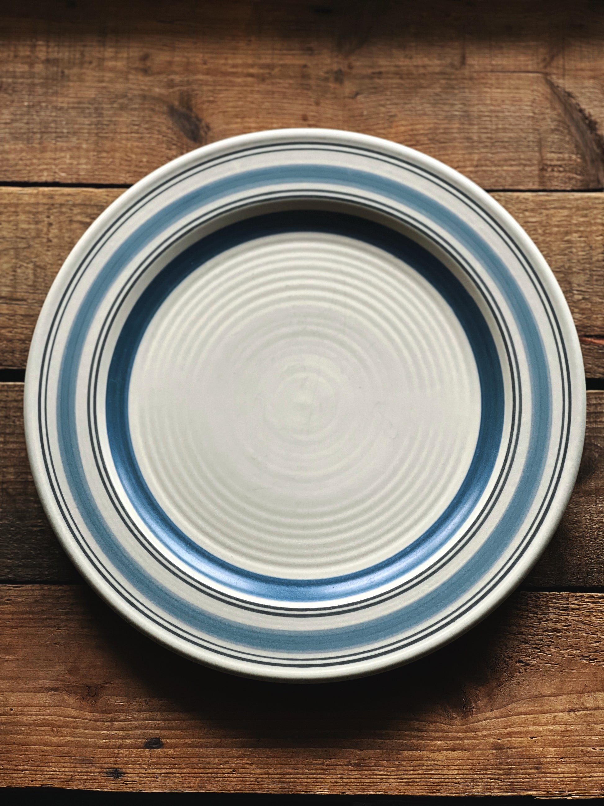 Ceramic plate with blue stripes on a wooden surface