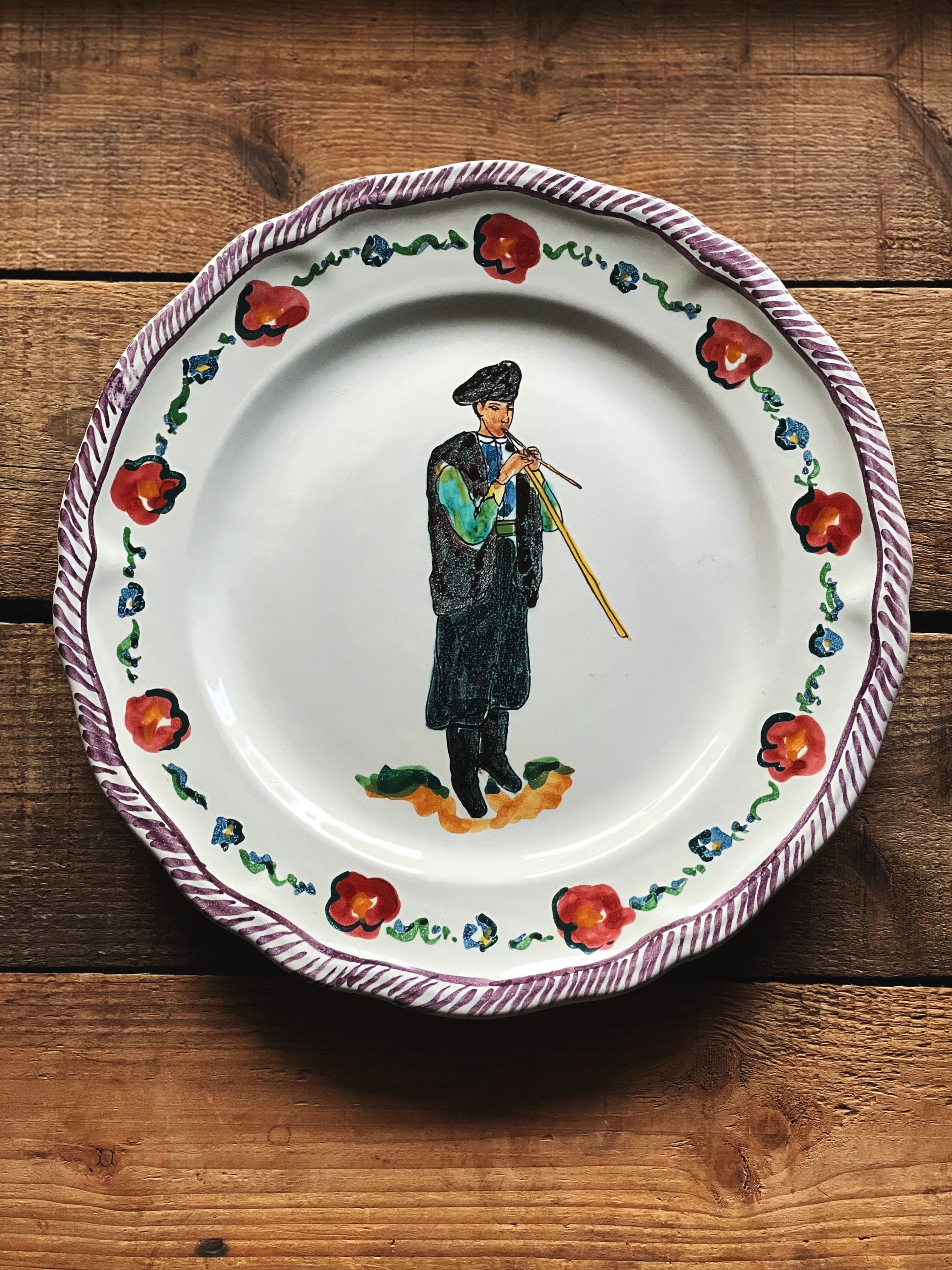 Decorative plate with a painted figure and floral design on a wooden surface