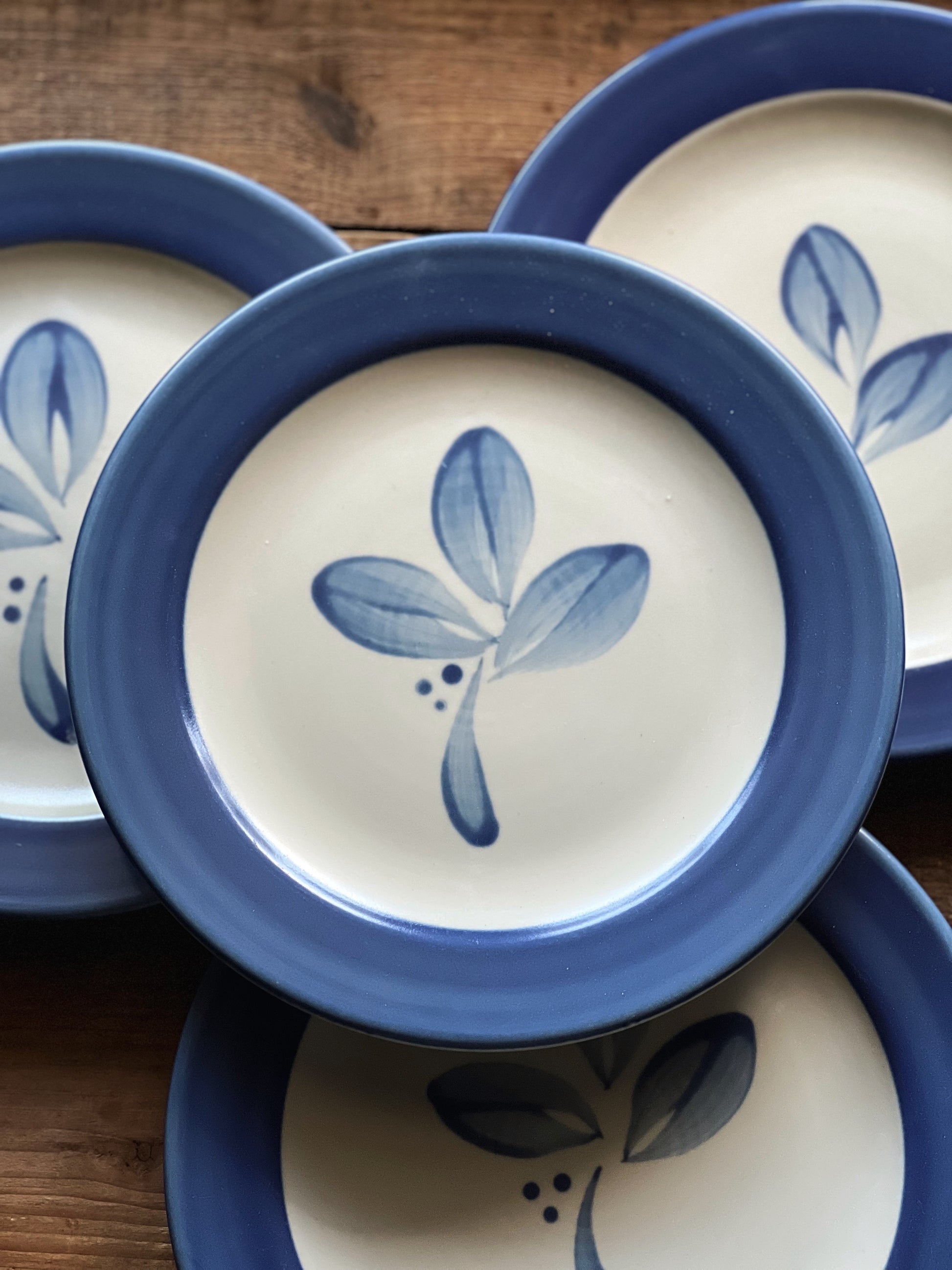 Set of ceramic plates with blue leaf design on a wooden surface