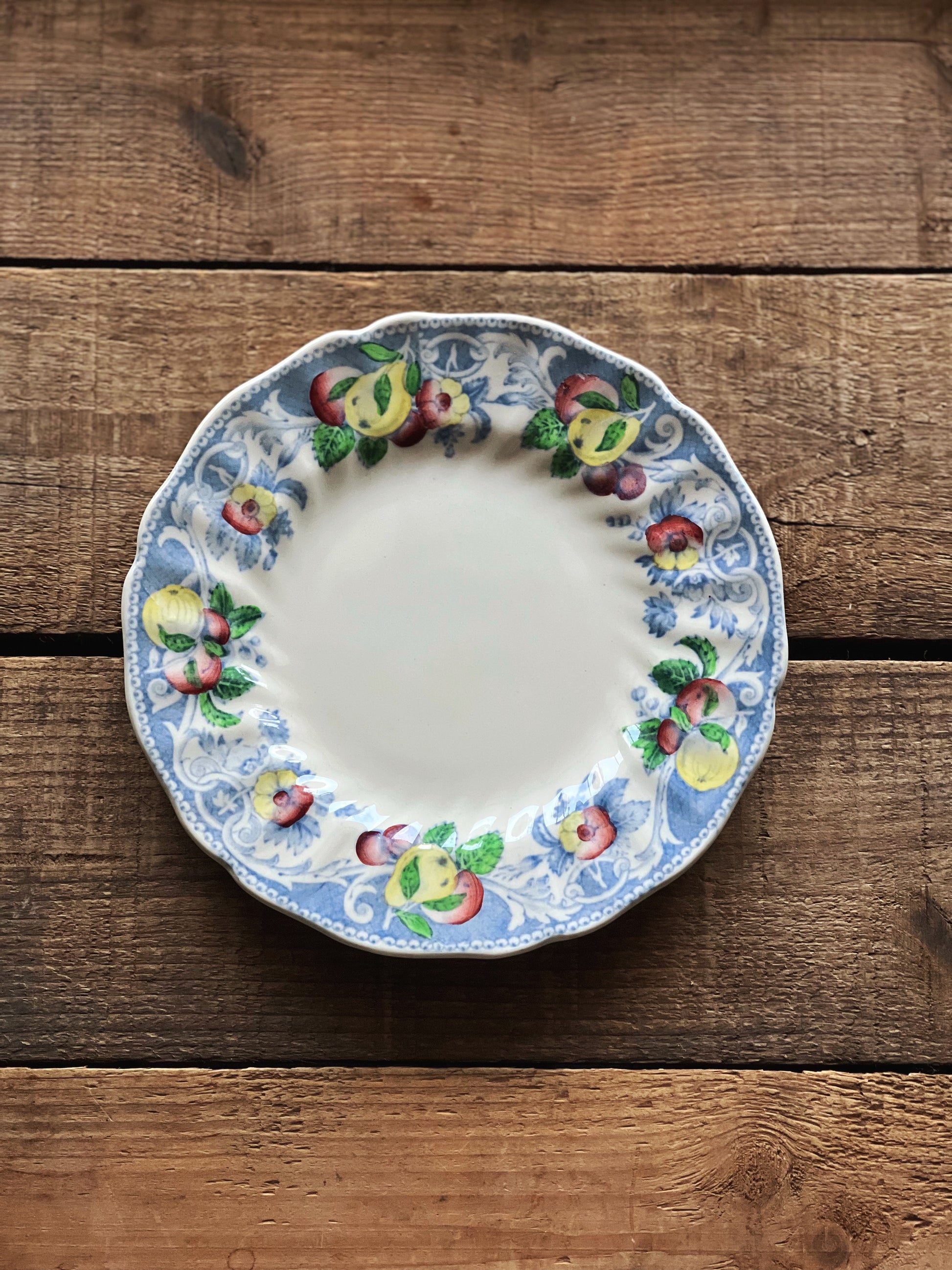 Decorative ceramic plate with fruit design on a wooden surface