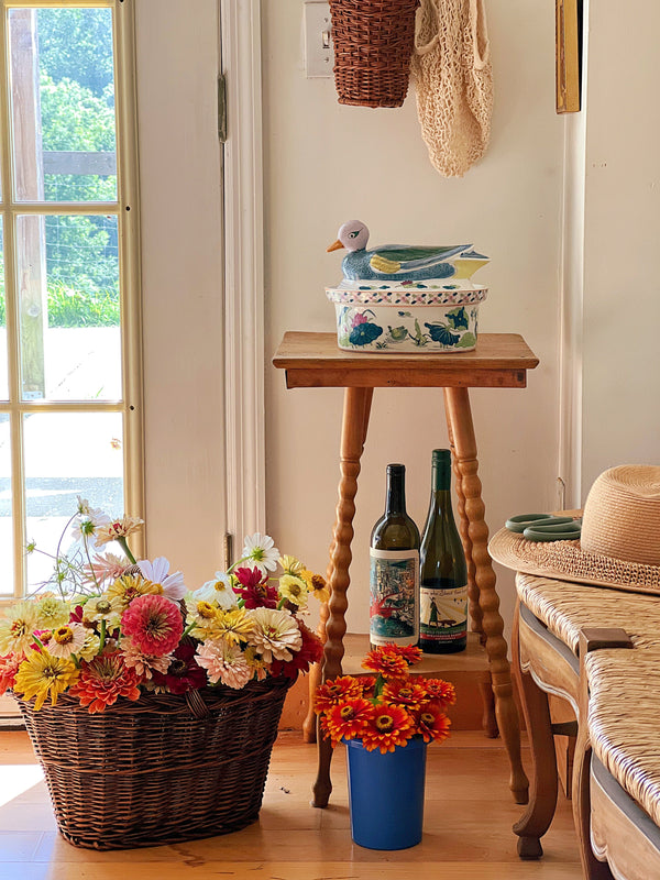 Collected vintage home decor styled with fresh flowers, woven baskets, warm wood furnishings, and natural window light