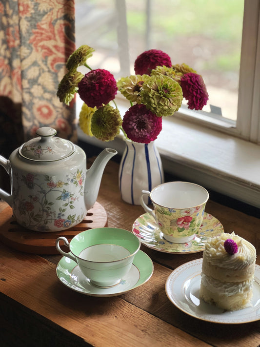 Vintage teacups and saucers with a teapot and small fancy cake