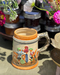 Decorative ceramic mug with colorful designs on a table with flowers in the background