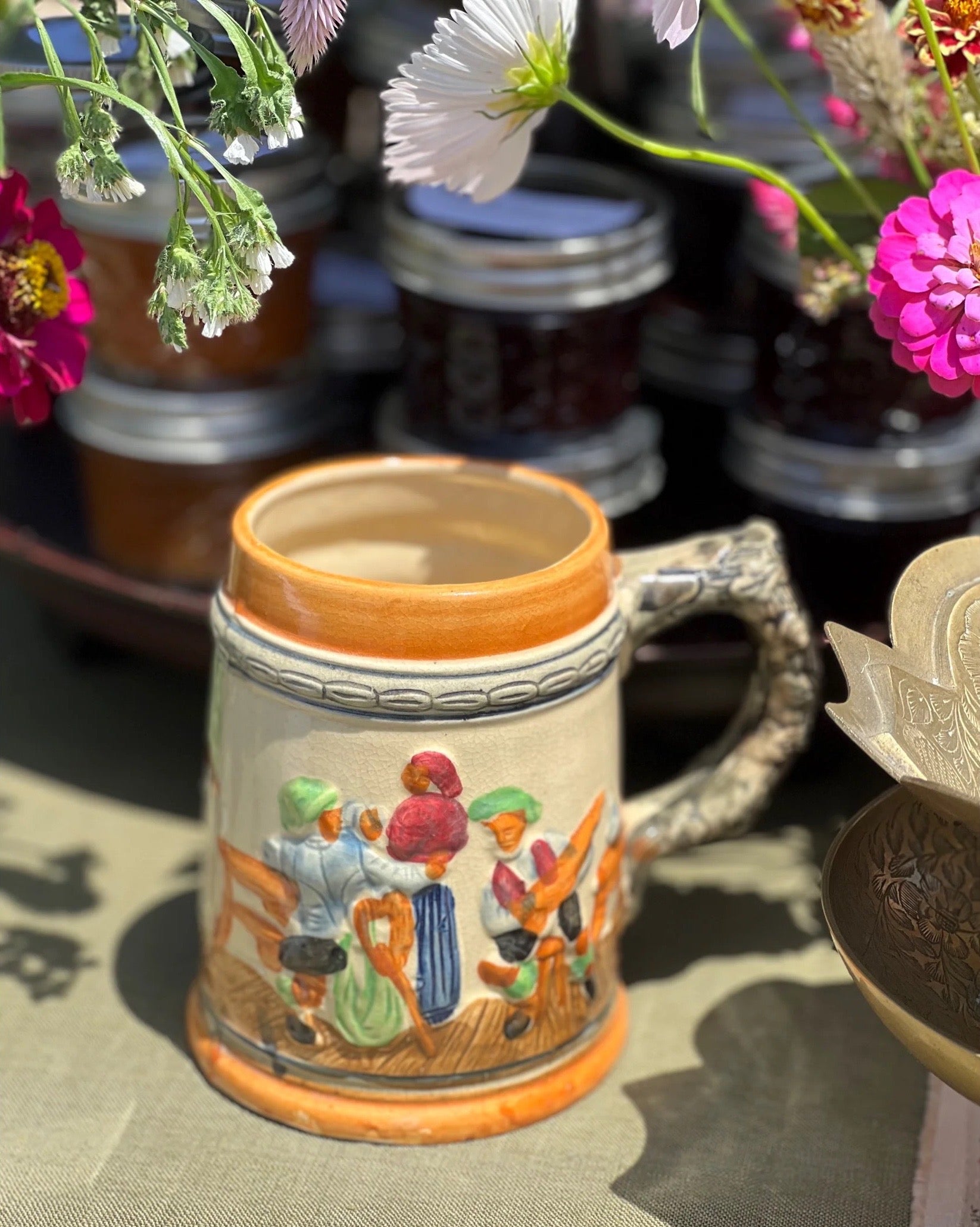 Decorative ceramic mug with colorful designs on a table with flowers in the background