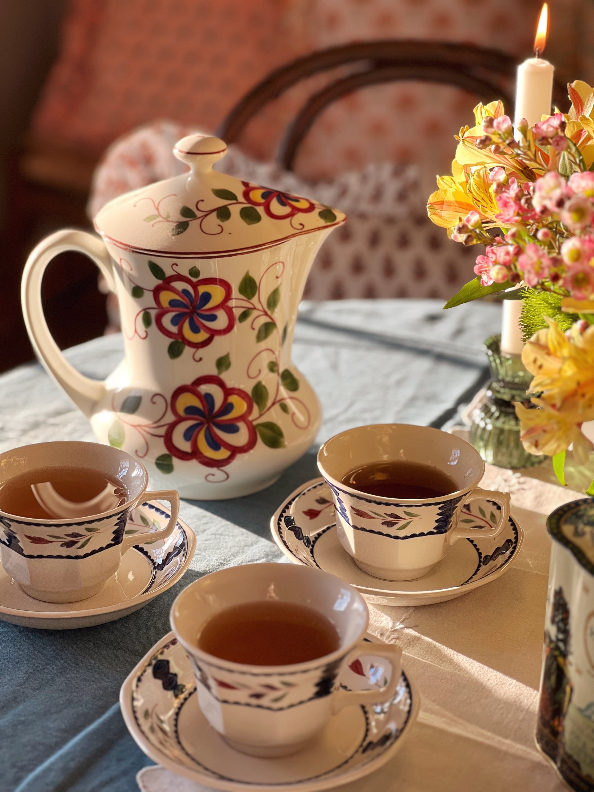 three teacup and saucer sets next to a teapot