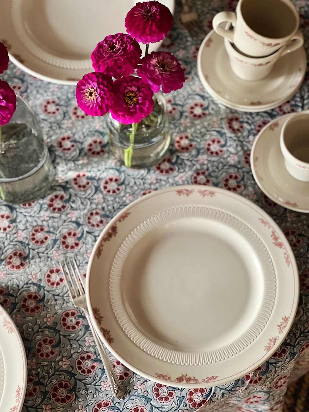 Dinner table setting with floral centerpiece on a patterned tablecloth
