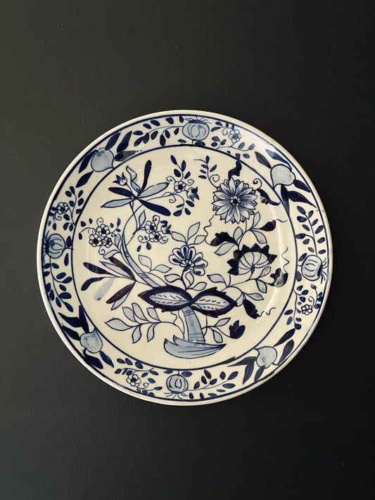 Blue Onion patterned wall plate hanging on a navy blue wall