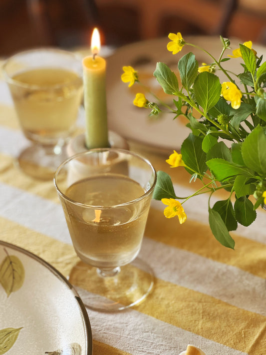 petite wine glasses filled with white wine on a table with yellow striped linens