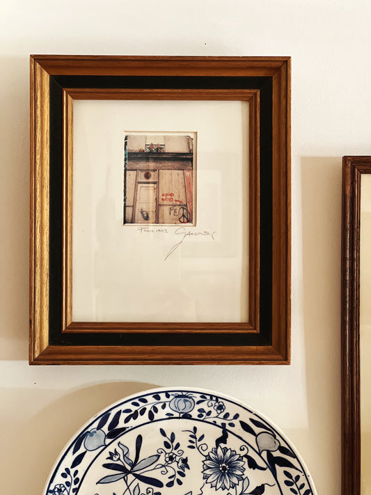 framed print of a Paris doorway hanging on a wall in a two tone wooden frame