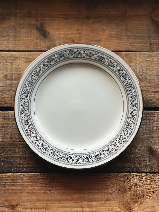 black and white salad plate with a scrollwork design and silver rim