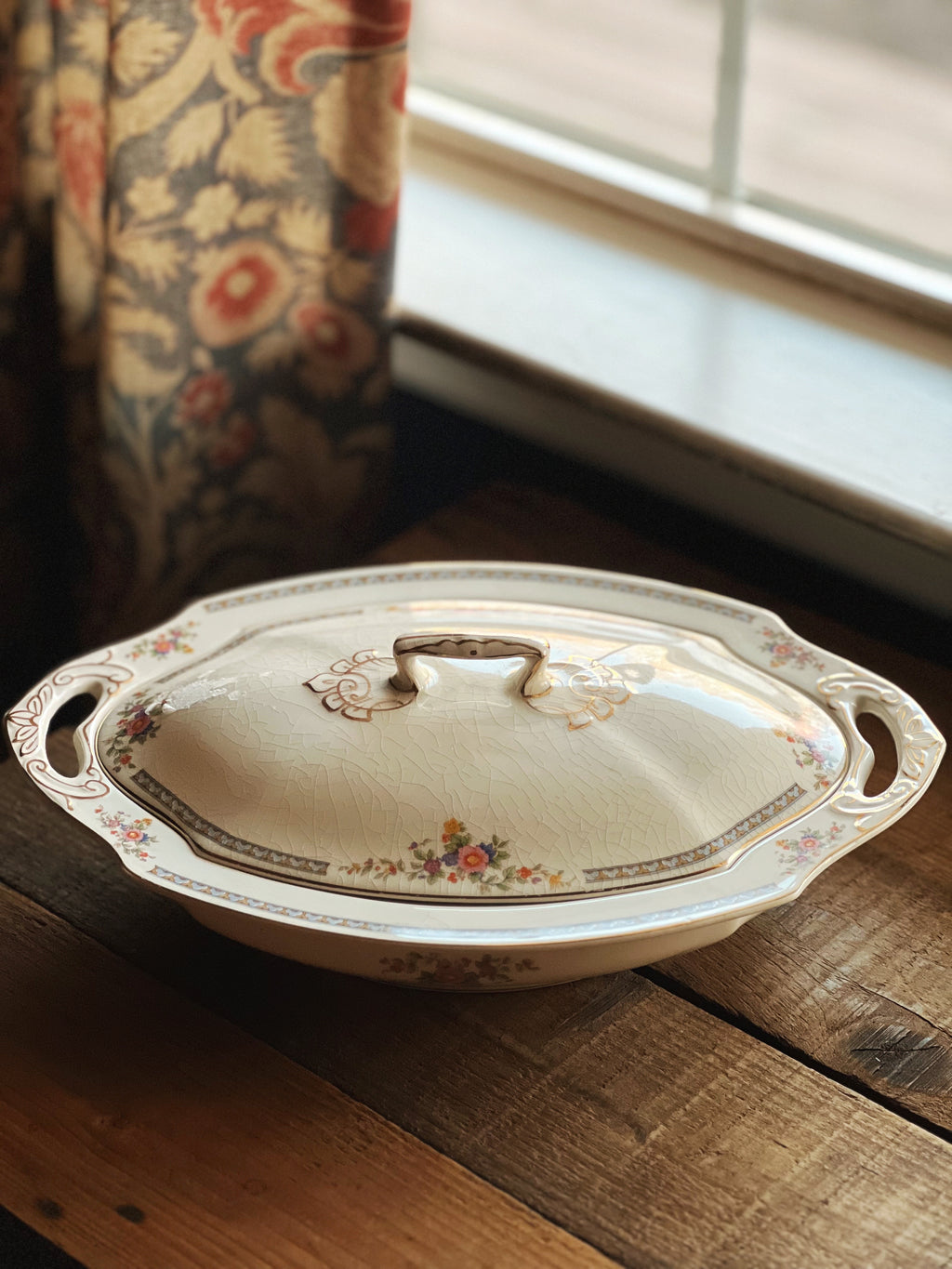 Bouquet of red and orange flowers in a rustic metal vase on a wooden surface.
