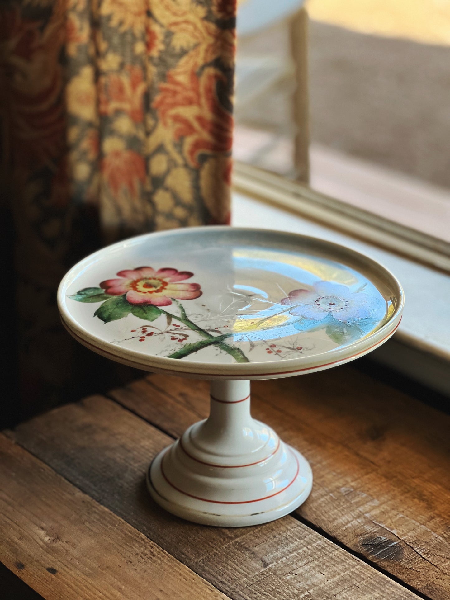 white milk glass cake stand with a pink floral design