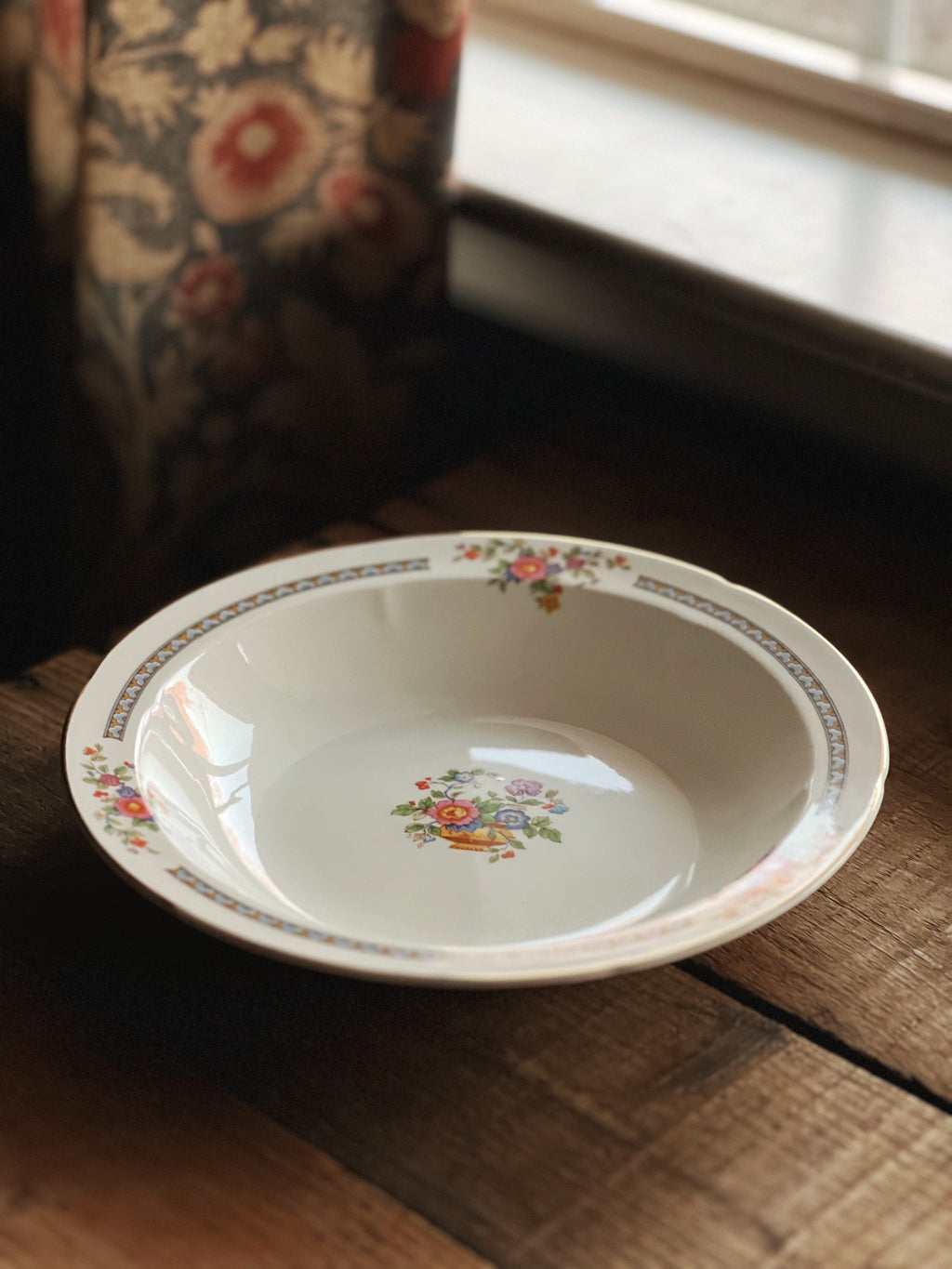 Floral-patterned ceramic dish on a wooden surface with a blurred background