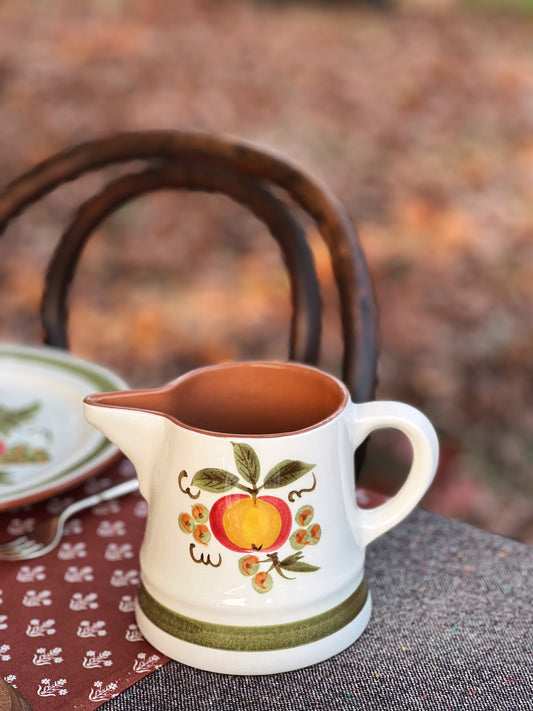 hand painted pitcher on a table outside in fall