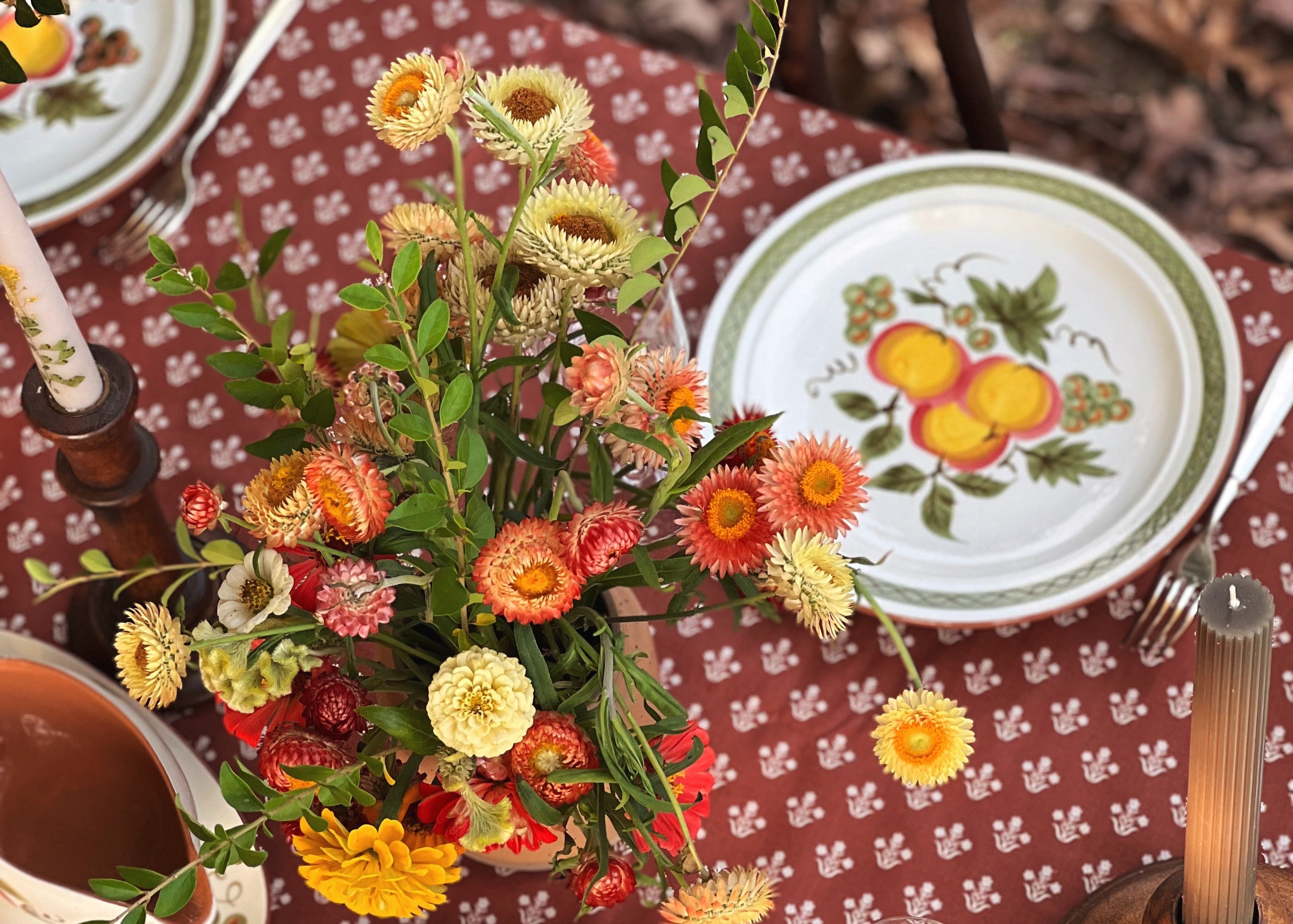Decorative table setting with floral centerpiece and patterned plates on a red tablecloth.