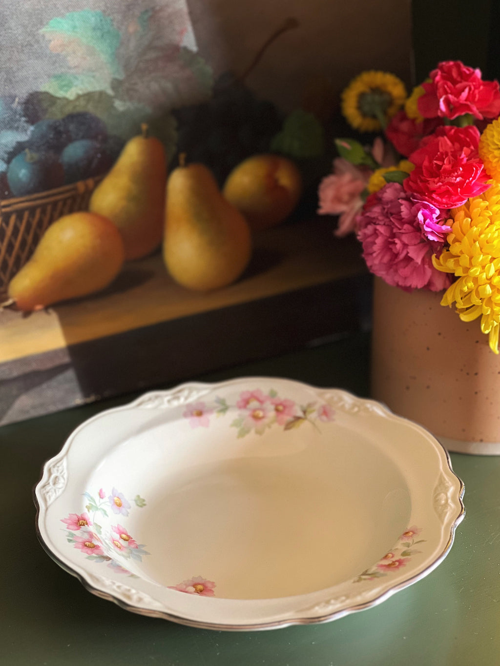 Vintage Homer Laughlin Virginia Rose rimmed soup bowl styled with fruit and flowers on green surface