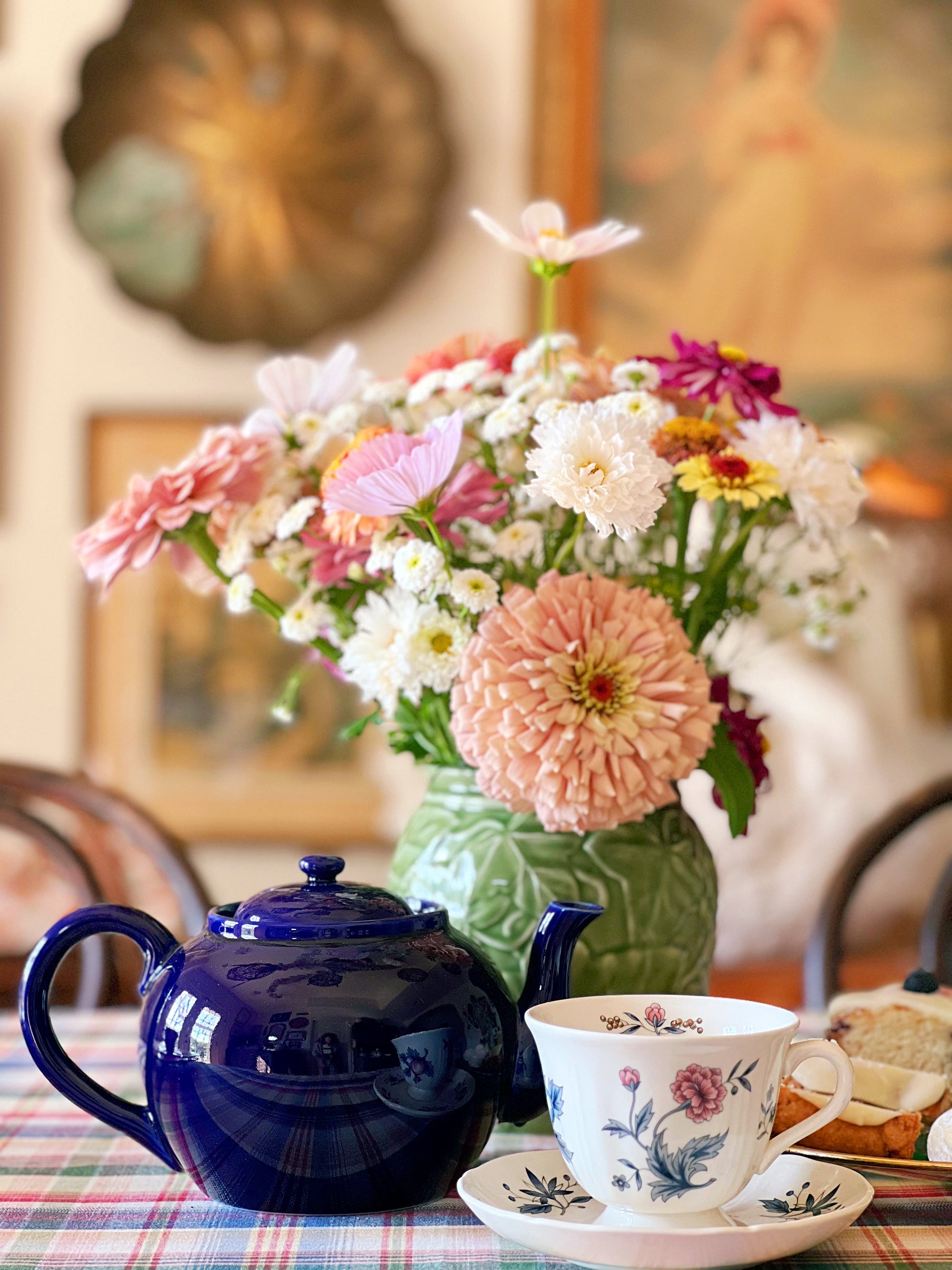navy blue teapot on a table with fresh flowers and a teacup & saucer