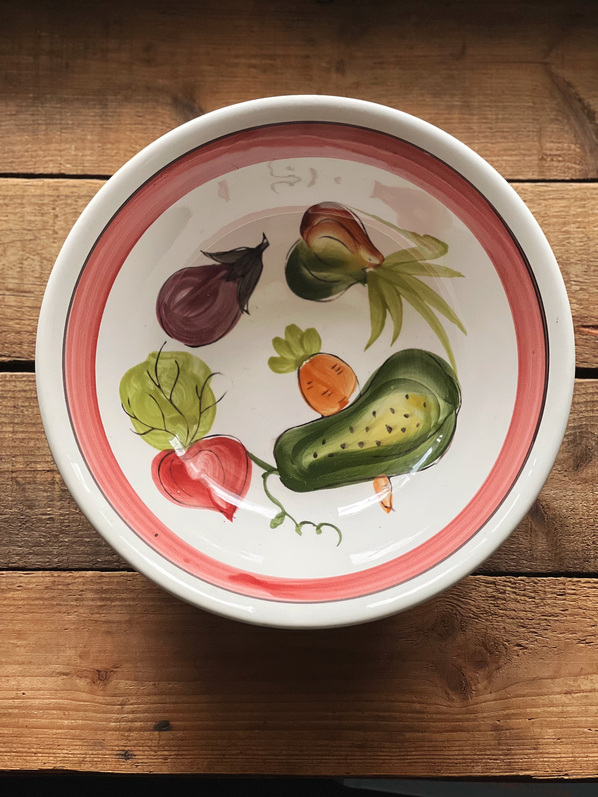 Ceramic bowl with vegetable designs on a wooden surface