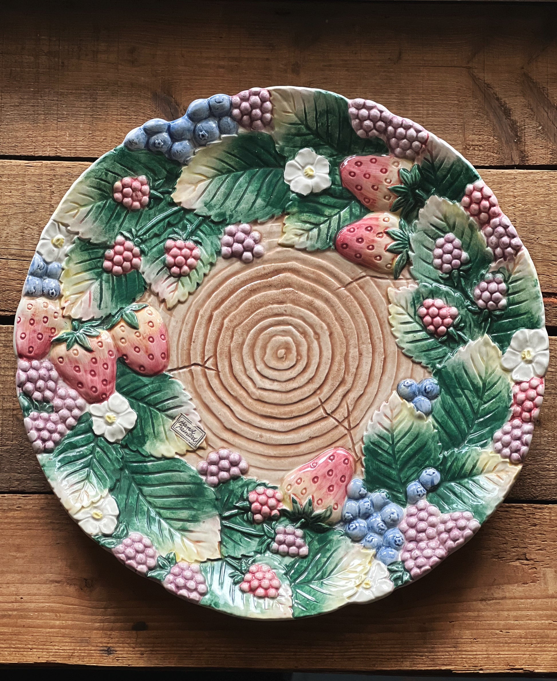 Decorative plate with strawberry and leaf design on a wooden surface