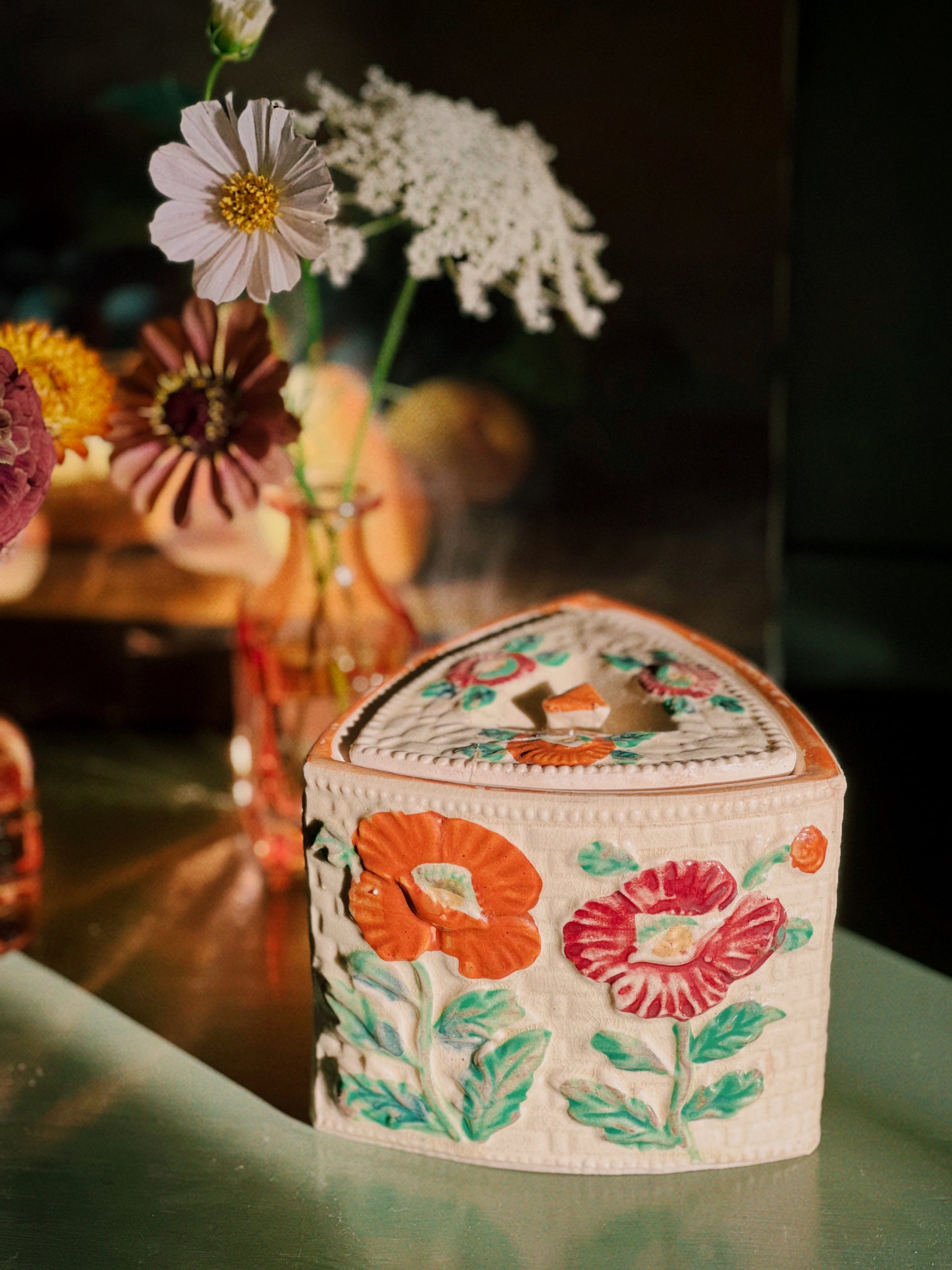 Decorative box with floral patterns on a table with flowers in the background