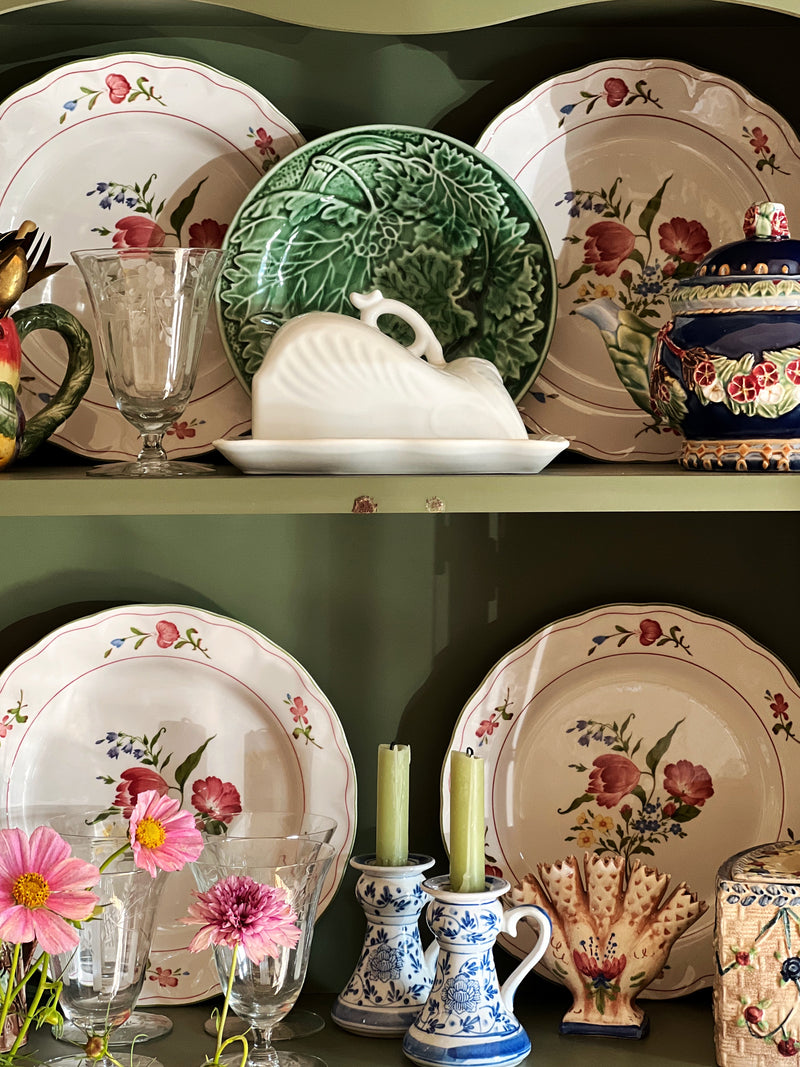 Collection of decorative ceramic items including plates, a green dish, and a white swan on a shelf.