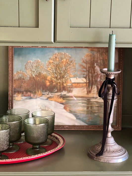 green wine glasses on a shelf with a candleholder