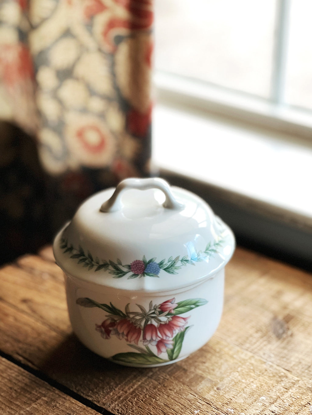 multi color floral sugar bowl on a wooden surface