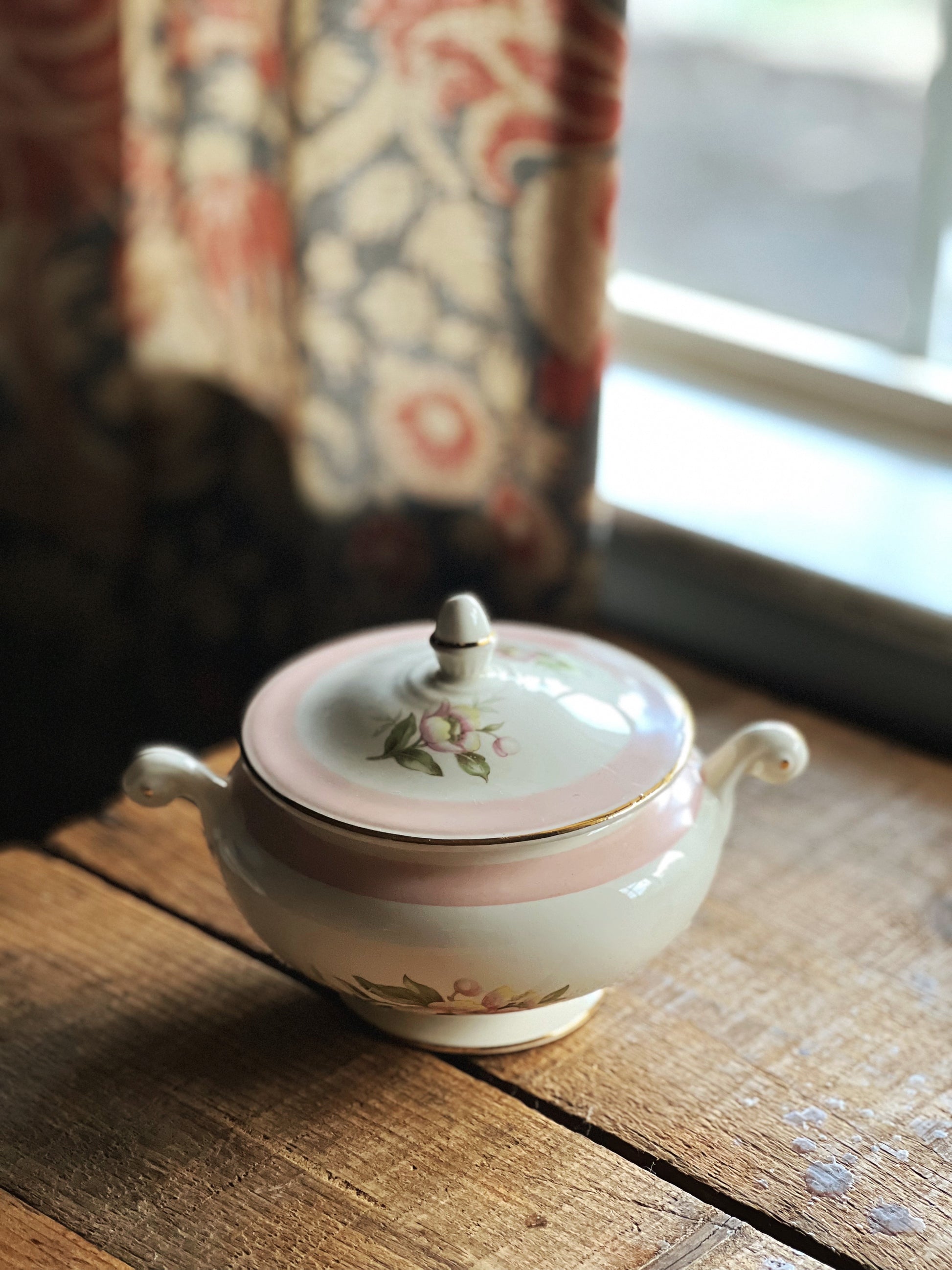 Decorative ceramic sugar bowl with floral patterns on a wooden surface