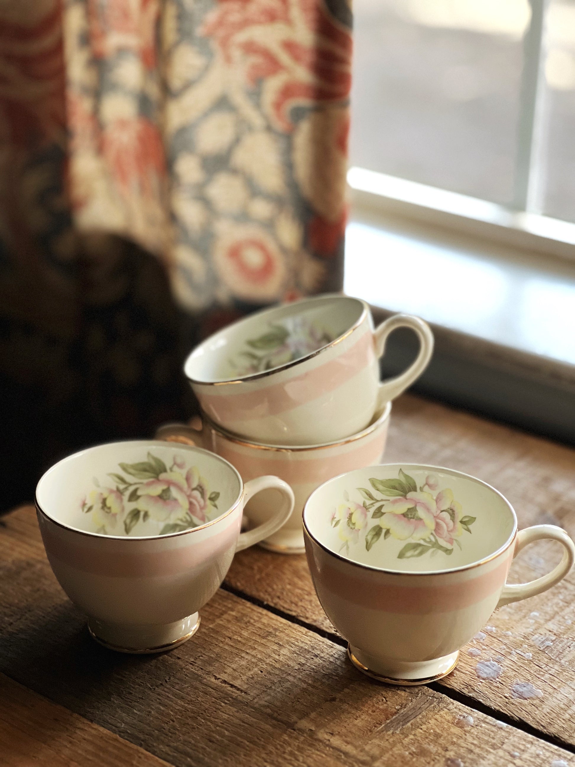 Set of three ceramic teacups with floral patterns on a wooden surface.