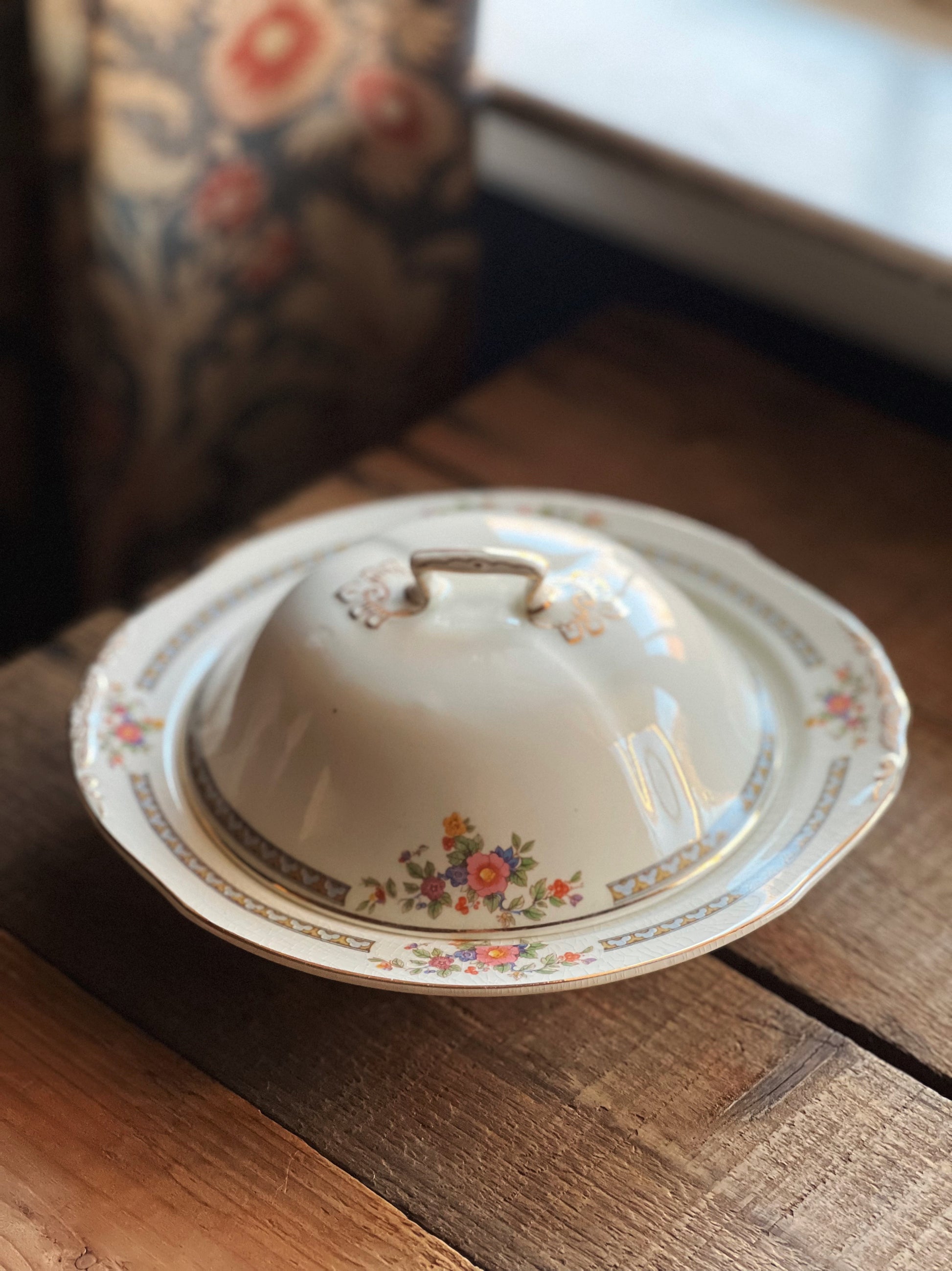 Decorative ceramic lid with floral patterns on a wooden surface