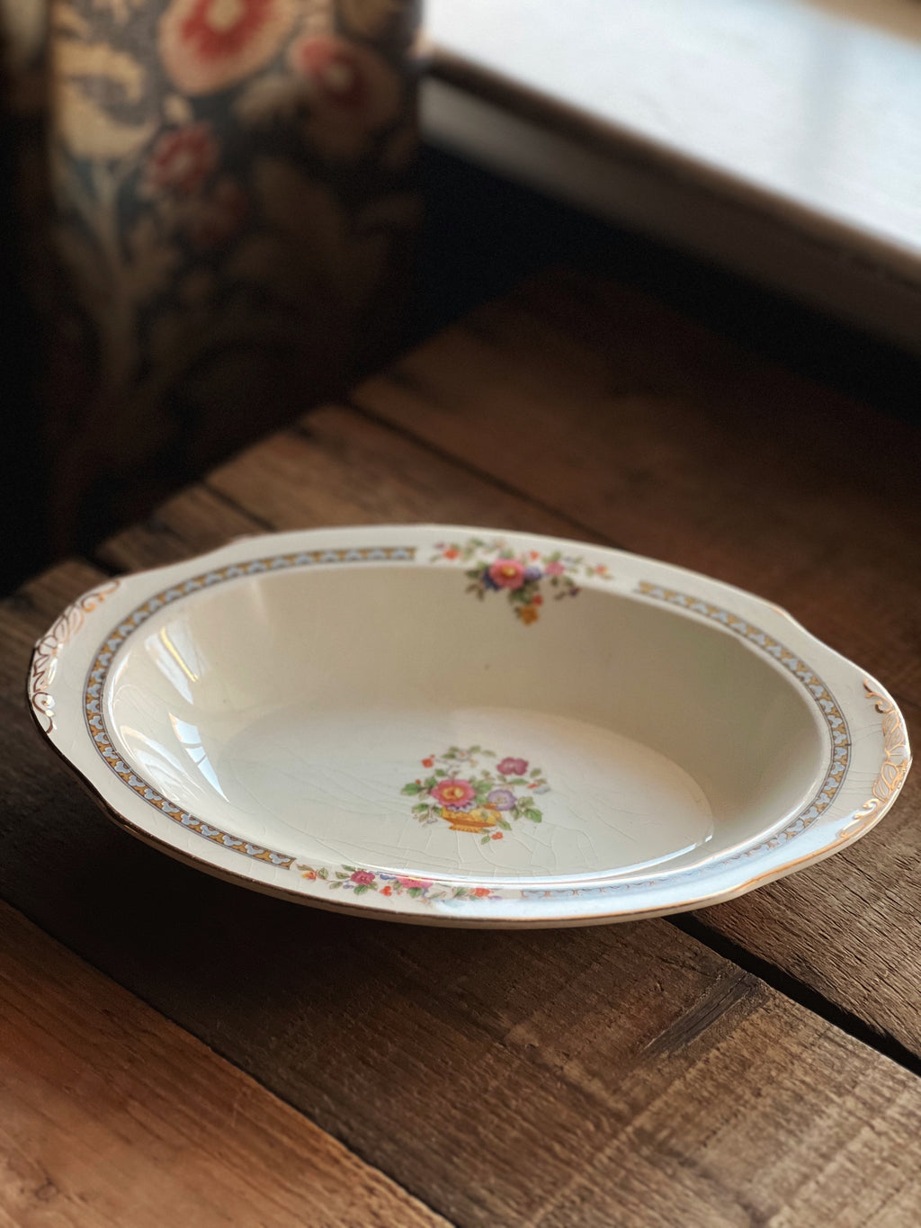 Decorative oval plate with floral patterns on a wooden surface