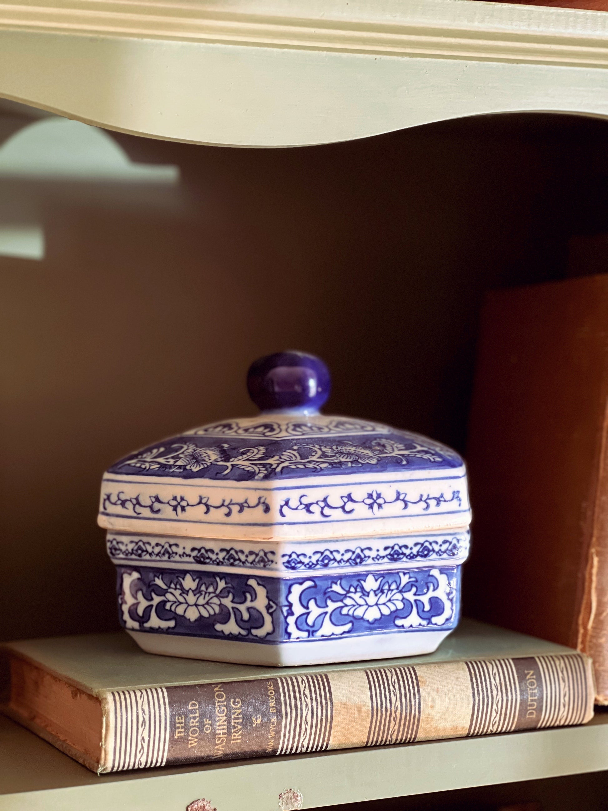 Blue and white ceramic hexagonal box on top of books