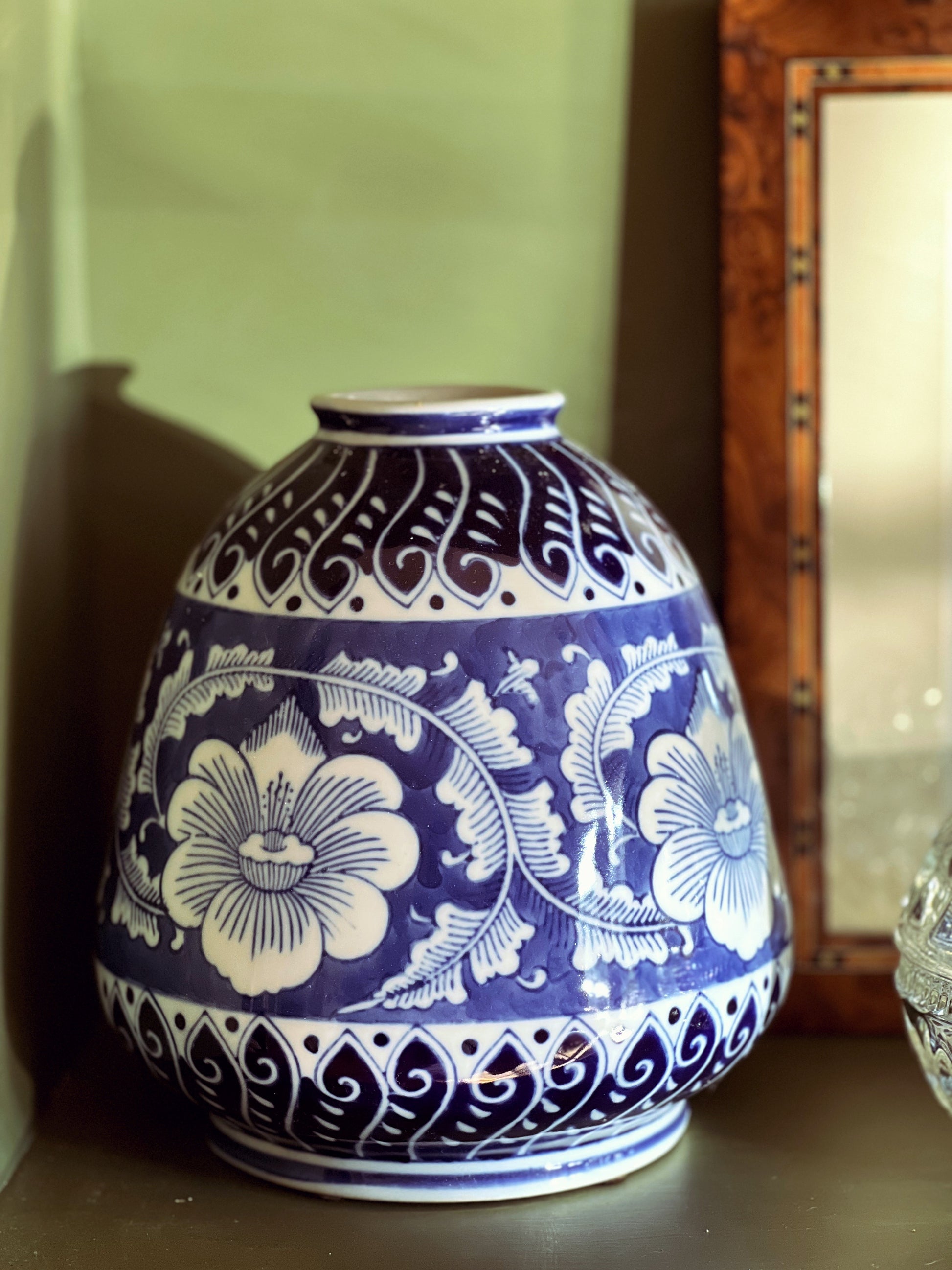 Blue and white ceramic vase with floral patterns on a wooden surface.