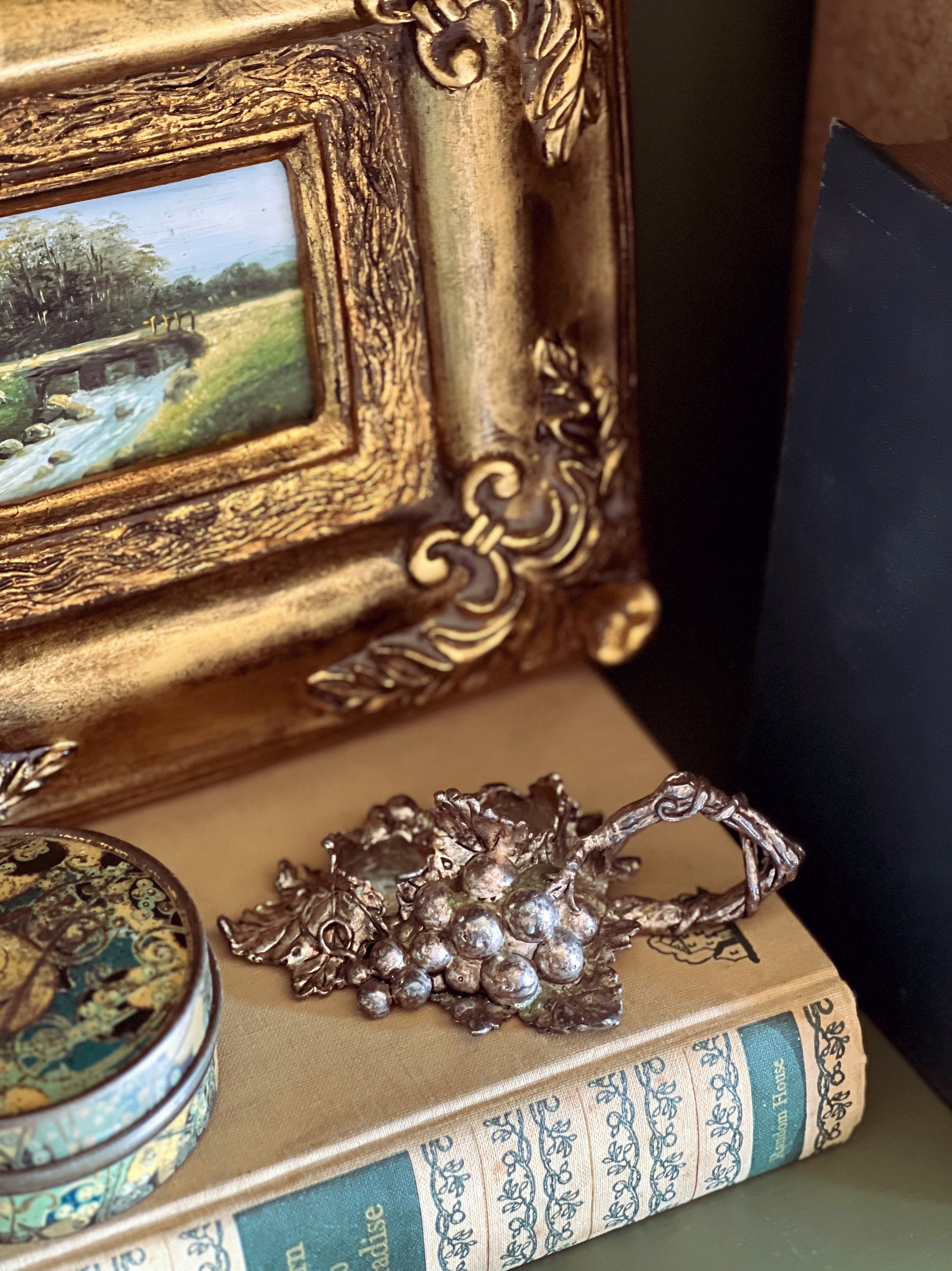 Decorative scene with a gold frame, jewelry, and books on a dark surface