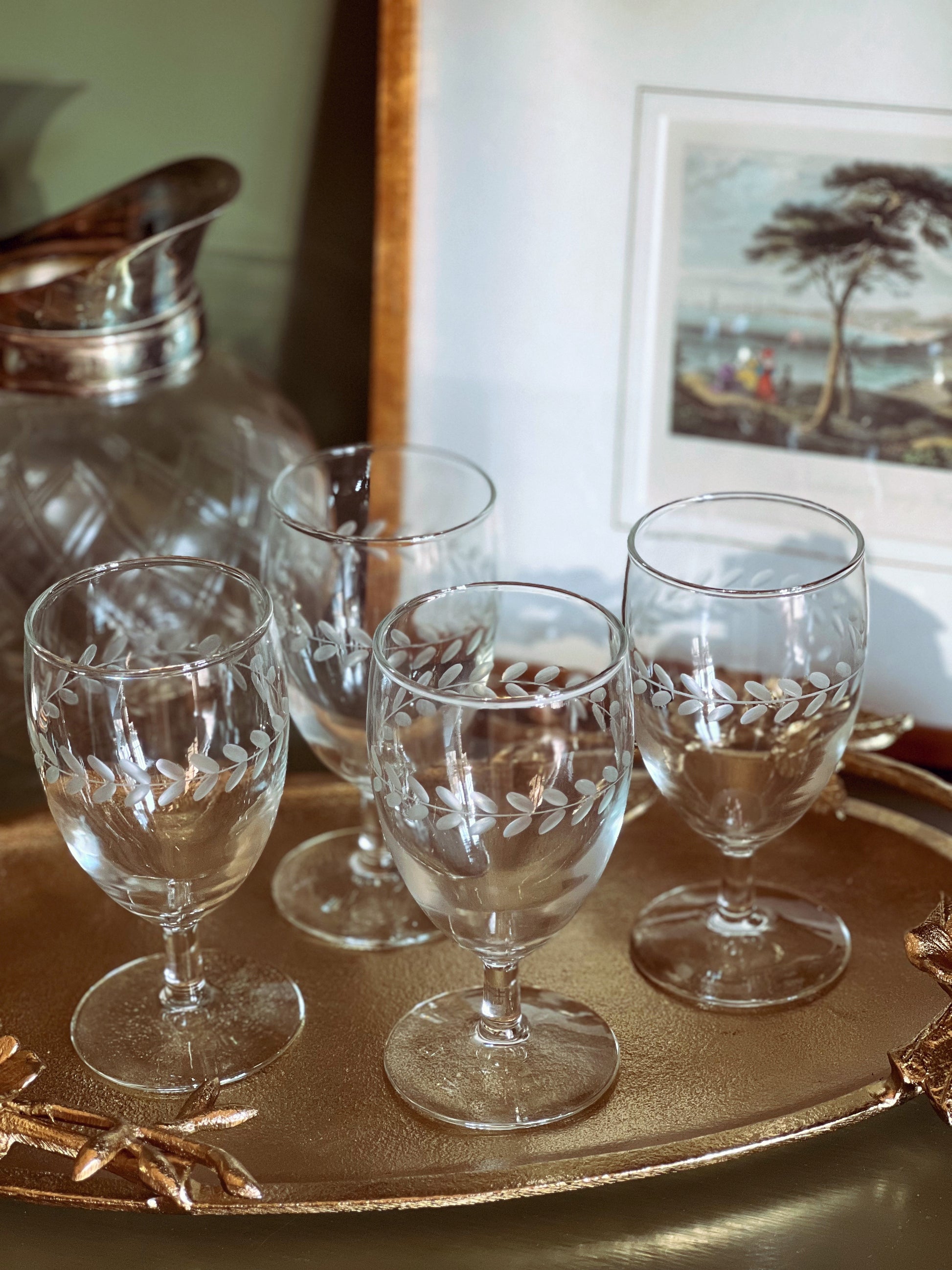 Set of etched glass wine glasses on a decorative tray with a blurred background