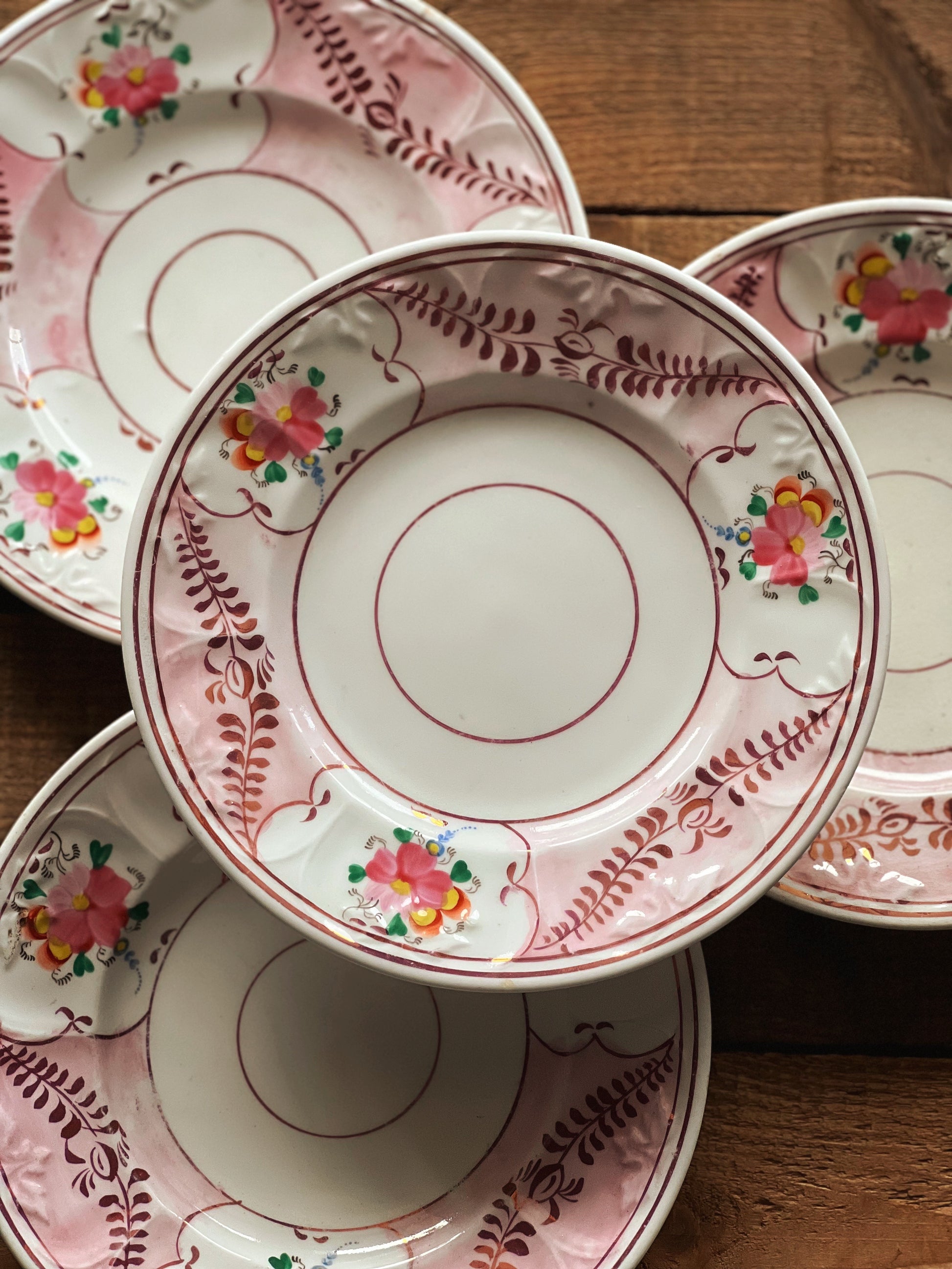 Stack of decorative ceramic plates with floral and leaf patterns on a wooden surface