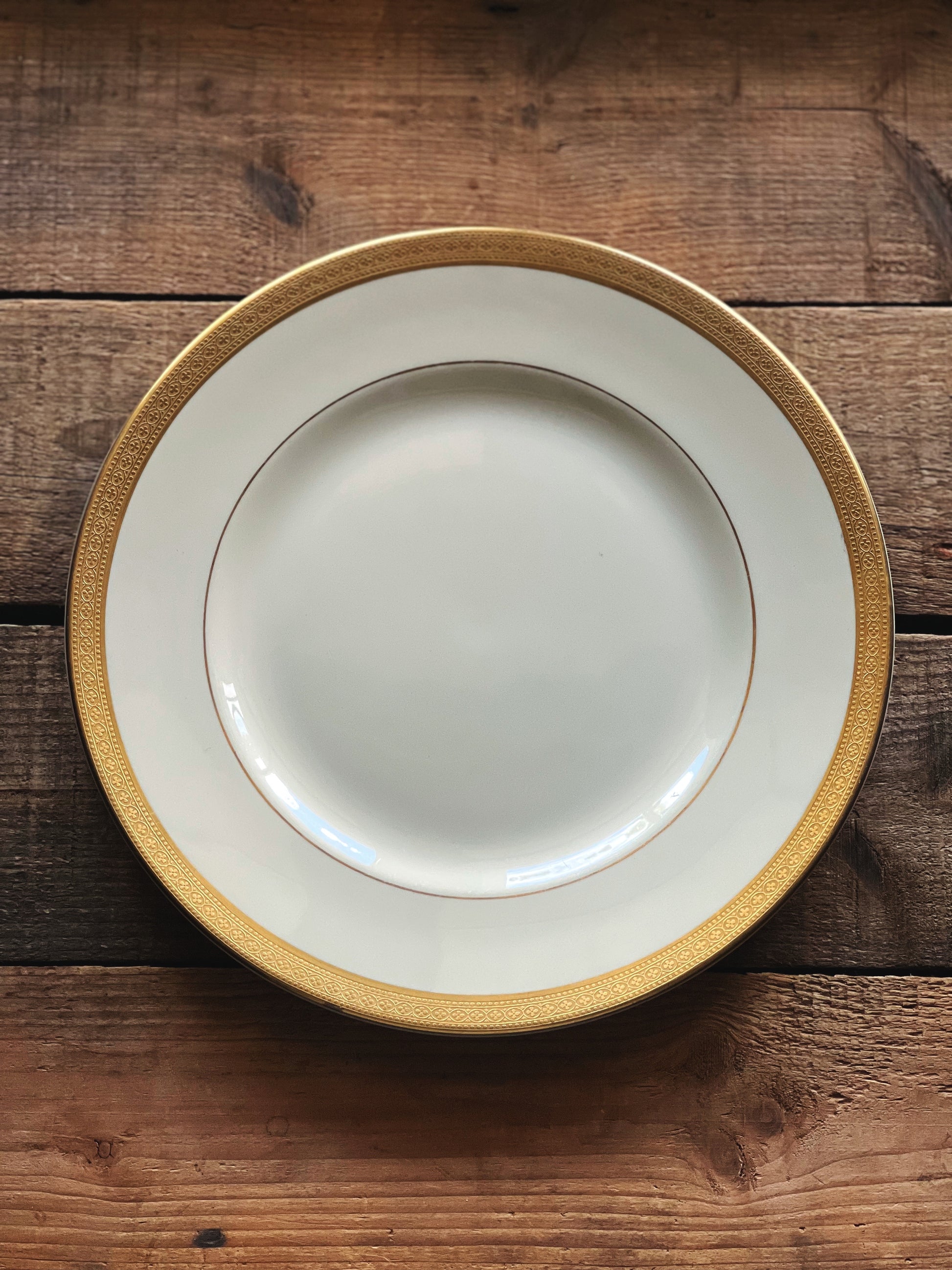 White plate with gold rim on a wooden surface