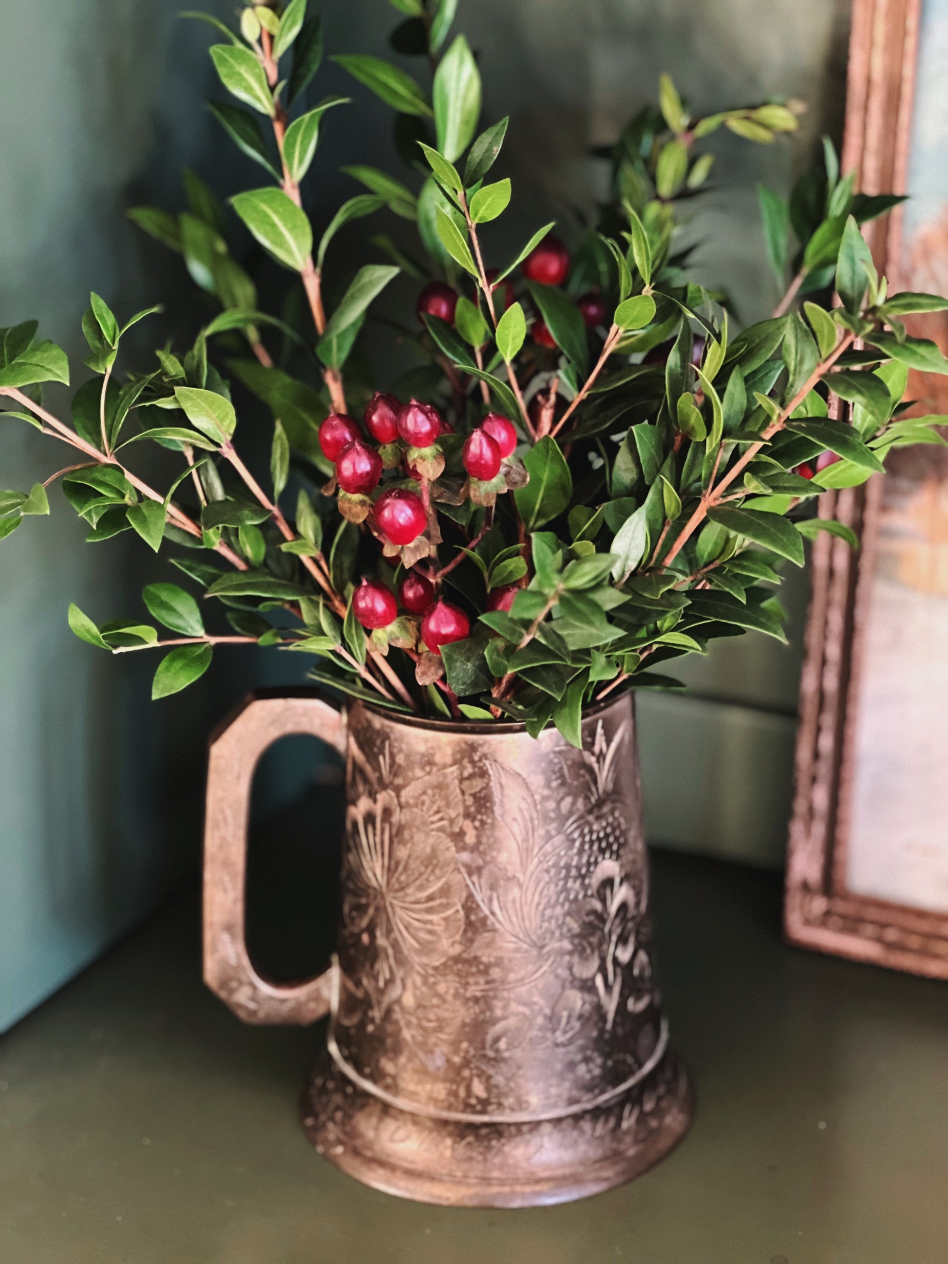 engraved brass tankard full of greens and berries