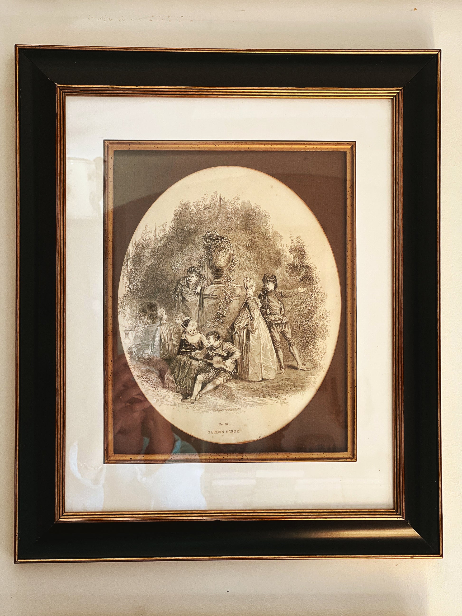 Framed vintage print of a family scene with a woman and children outdoors.