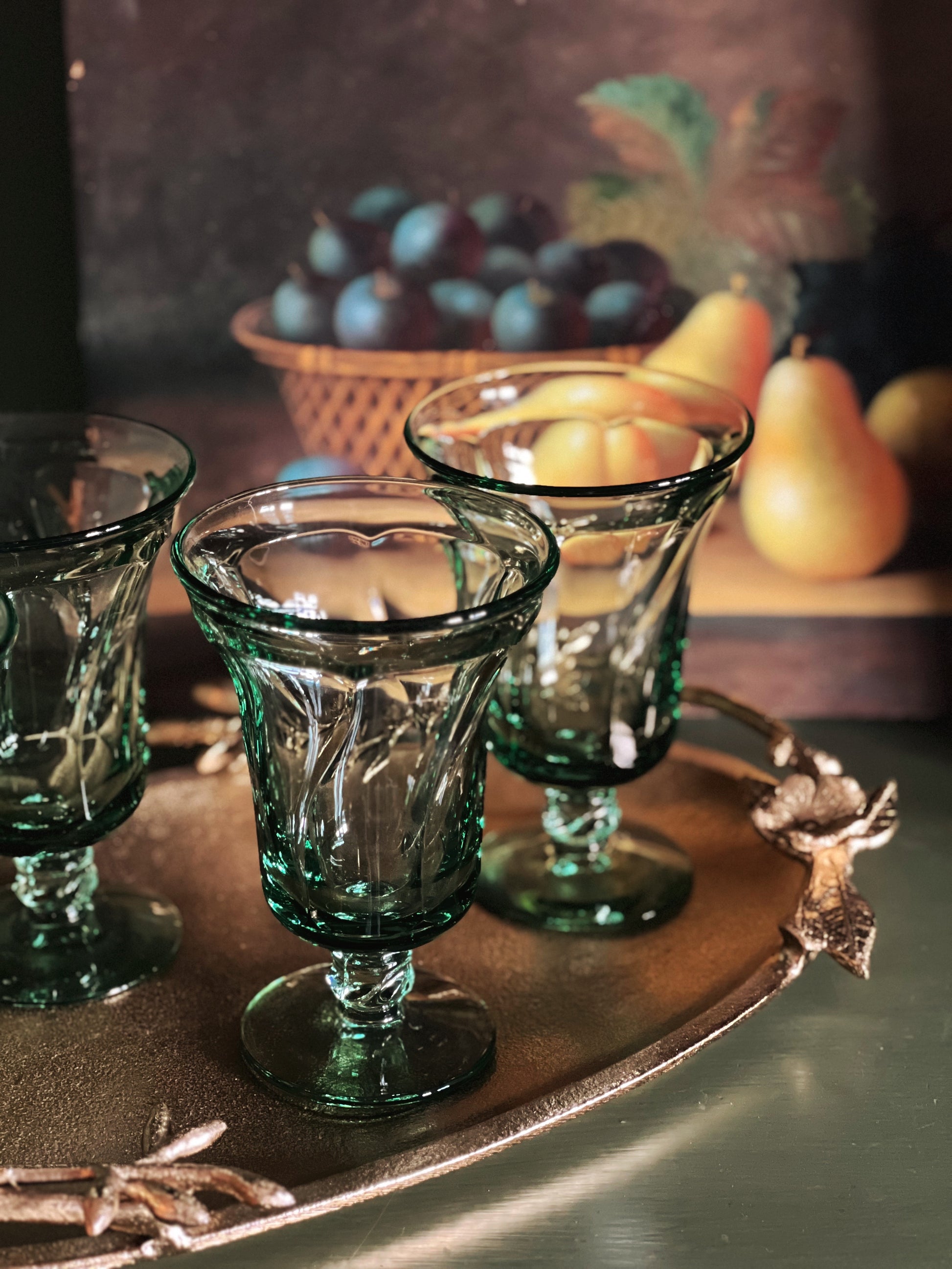 green tea glasses on a gold tray with a still life painting in the background