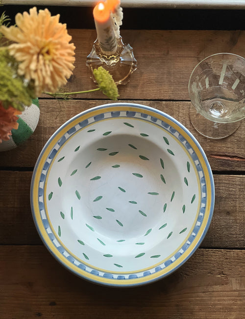 Decorative ceramic bowl with floral arrangement and candle on wooden surface