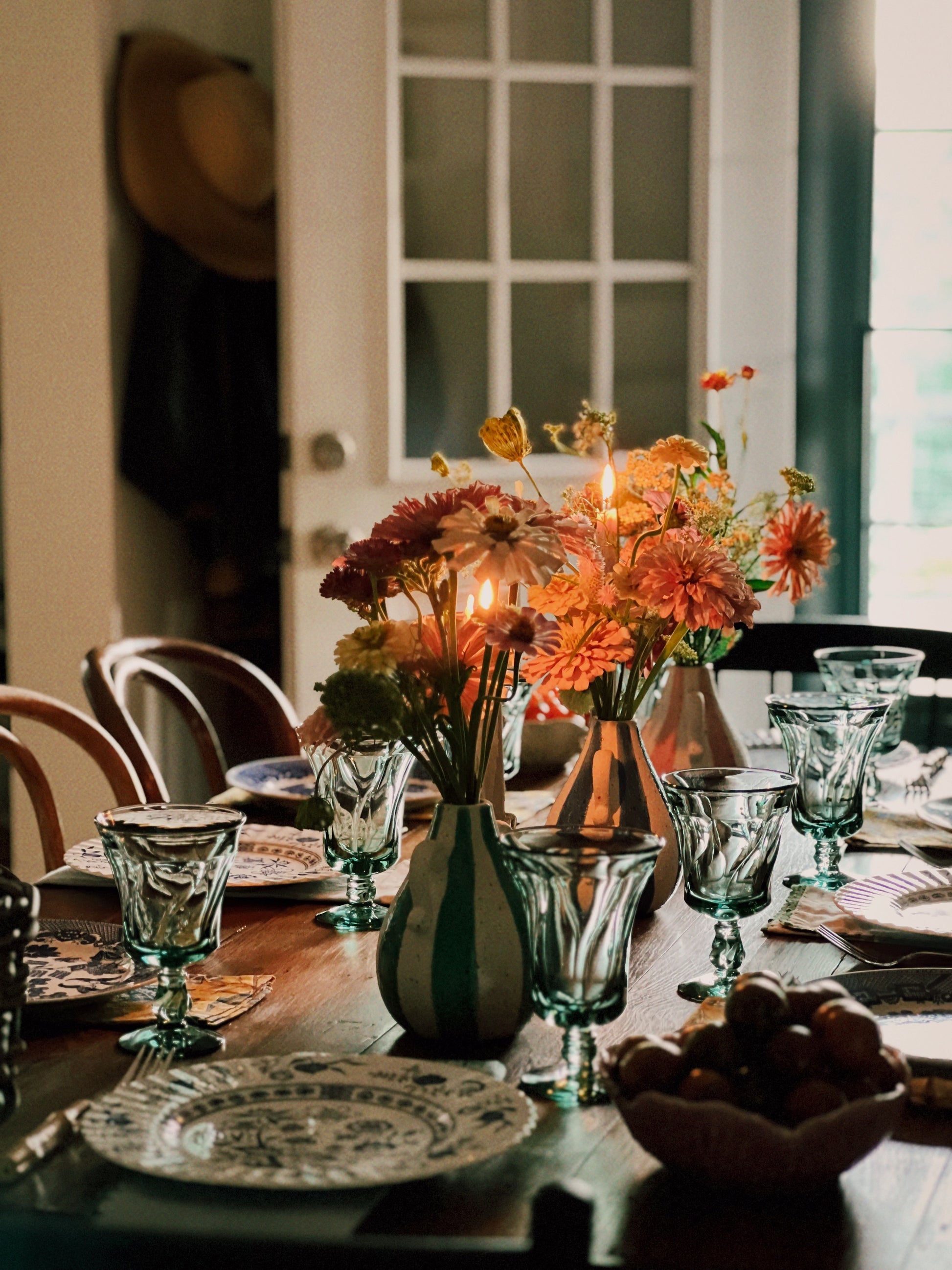 Dining table set with floral centerpieces and glassware in a cozy room.