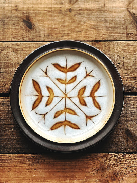 brown rim stoneware salad plate with a design that looks like a snowflake