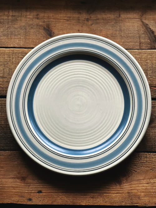 Ceramic plate with blue stripes on a wooden surface