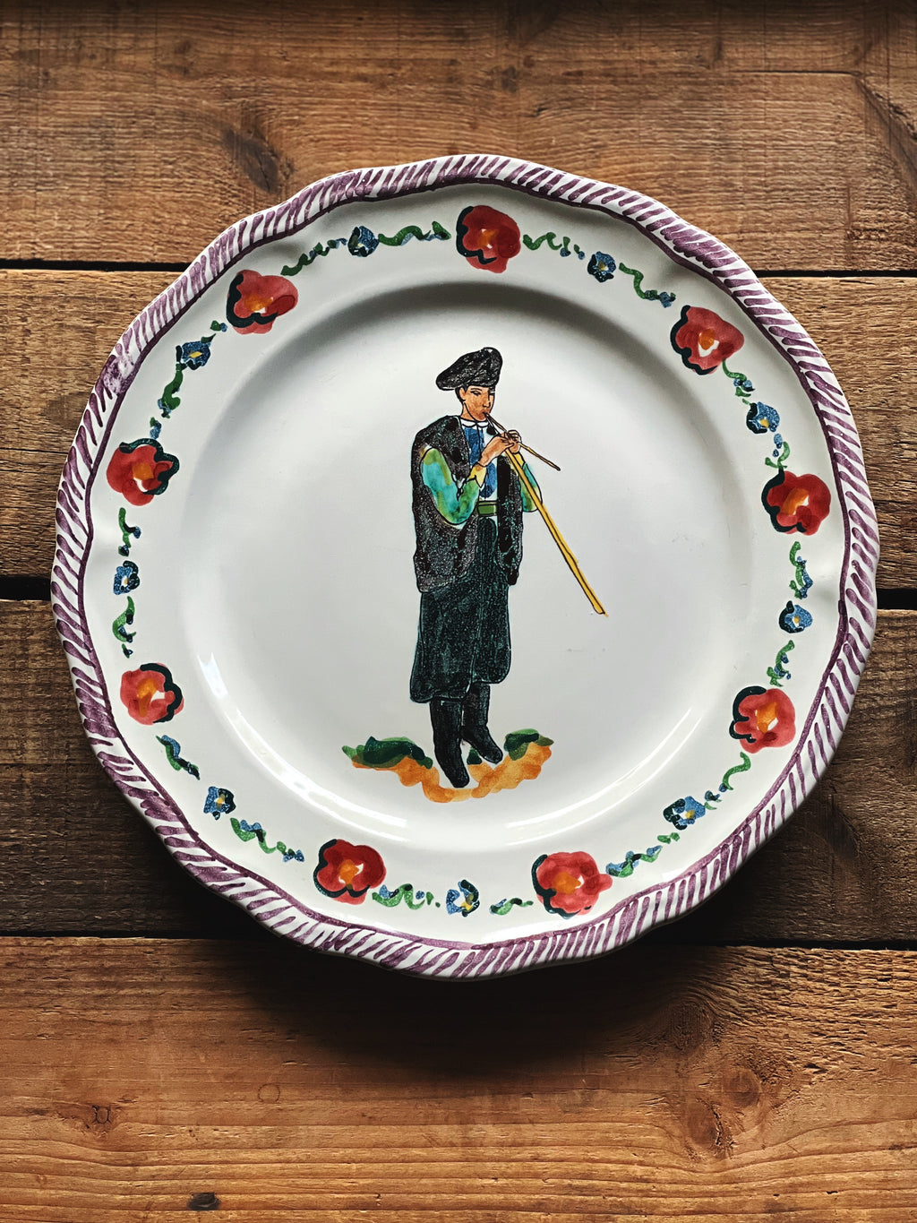 Decorative plate with a painted figure and floral design on a wooden surface