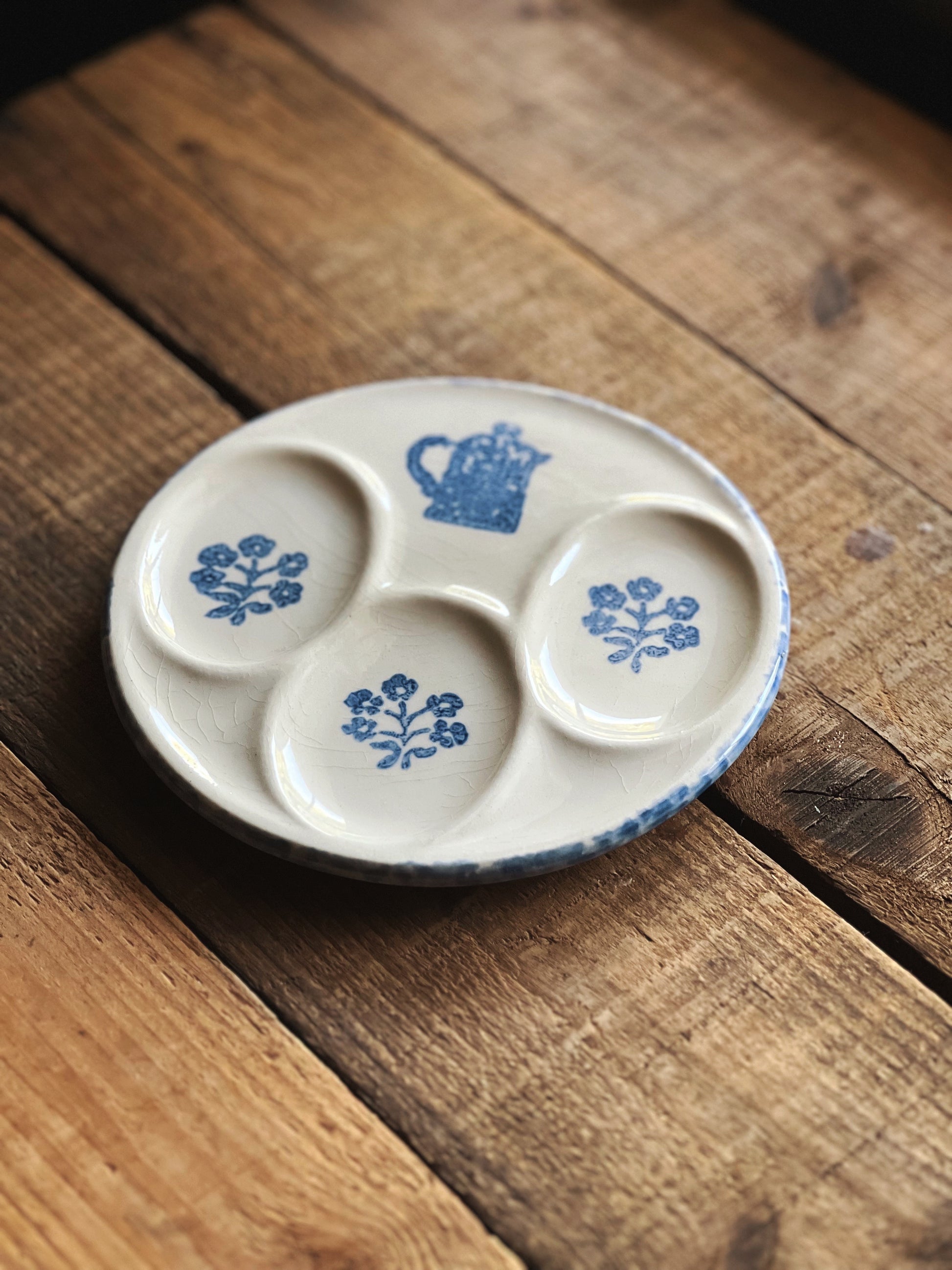 Ceramic dish with blue floral and teapot designs on a wooden surface